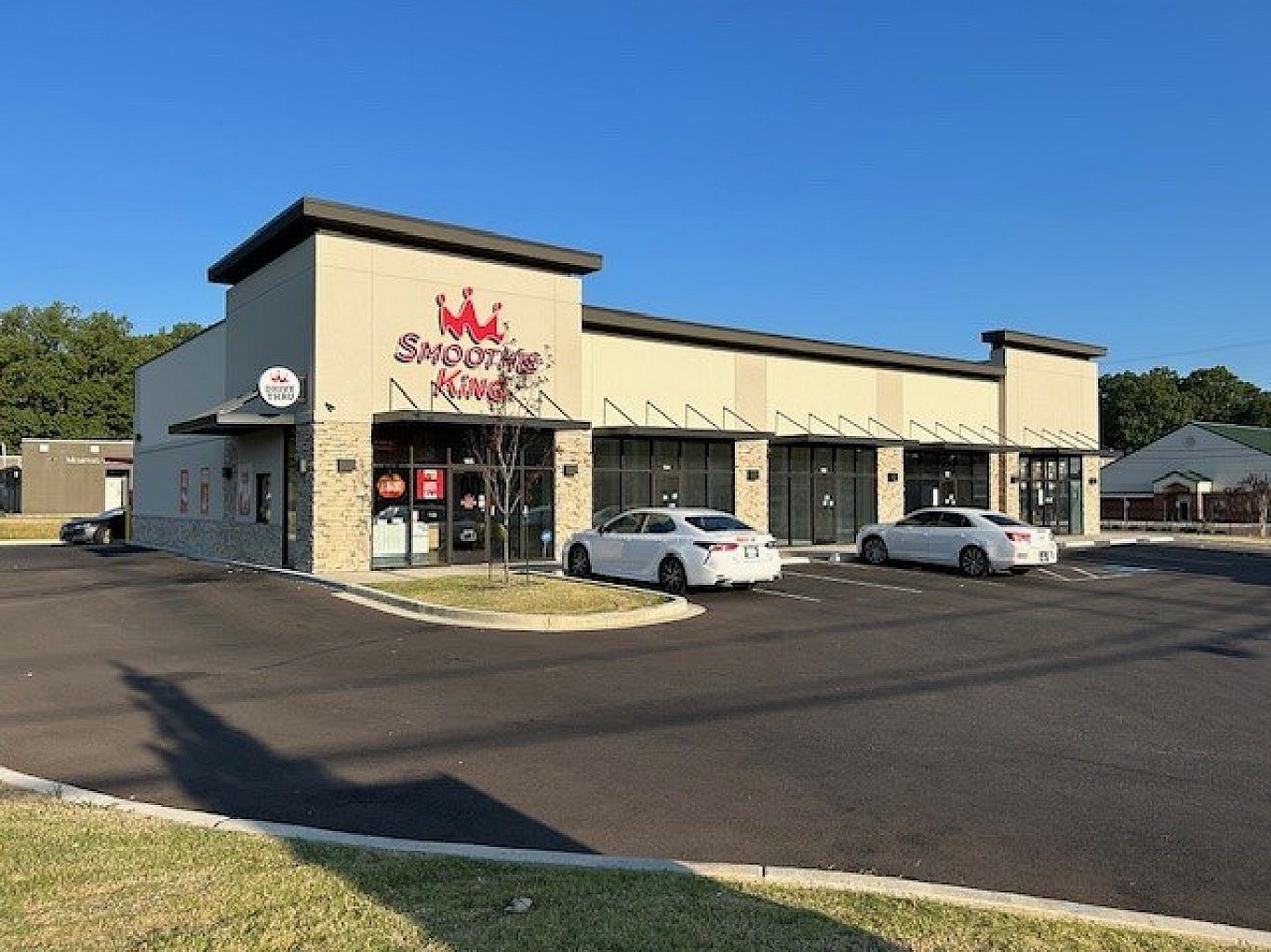 The exterior of a shopping center with a Smoothie King in the far left store.