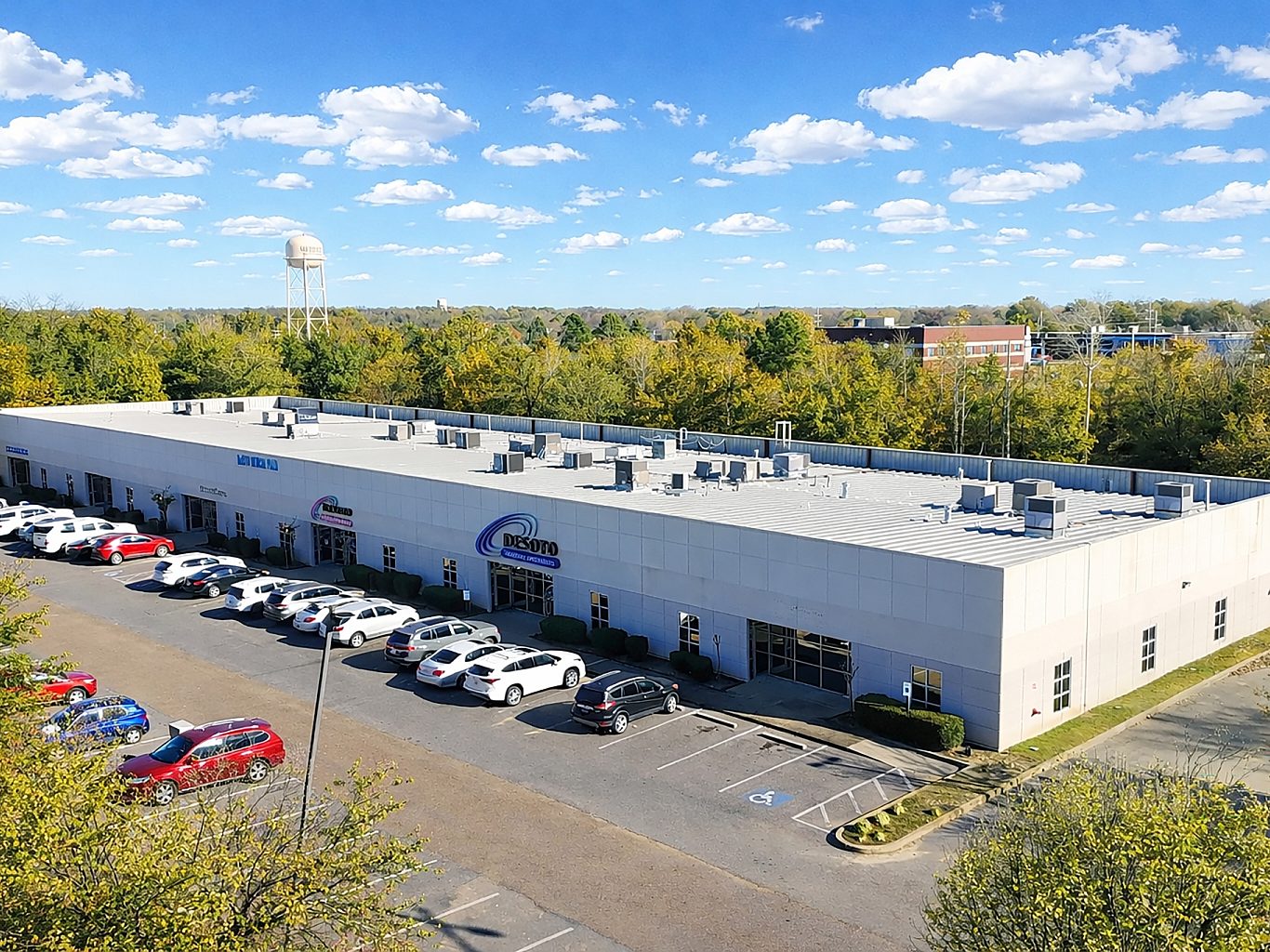 Aerial view of office buildings surrounded by trees with a water tower in the distance