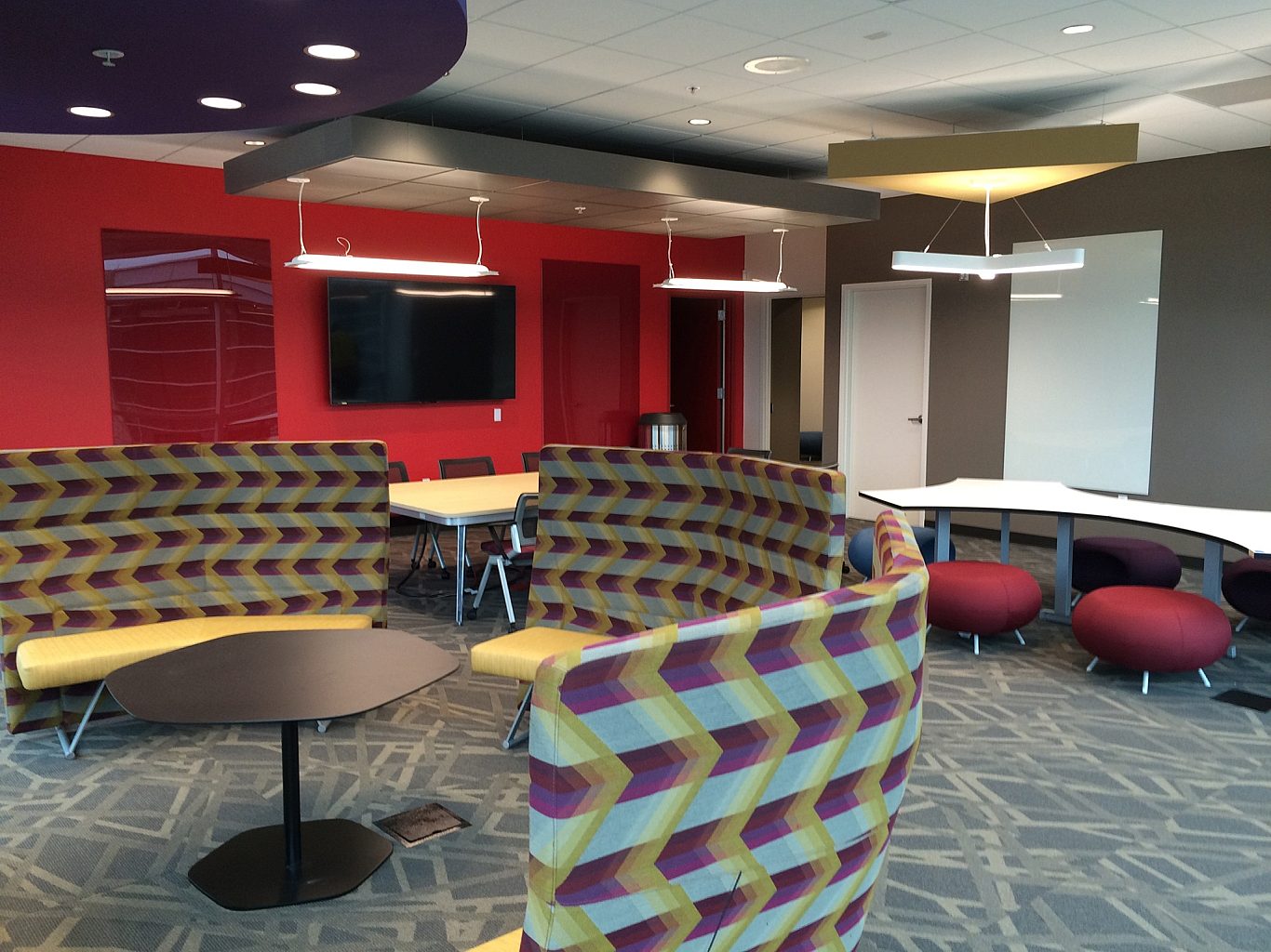 A corporate classroom with several seating options, including benches lining a wall and stools at a table.