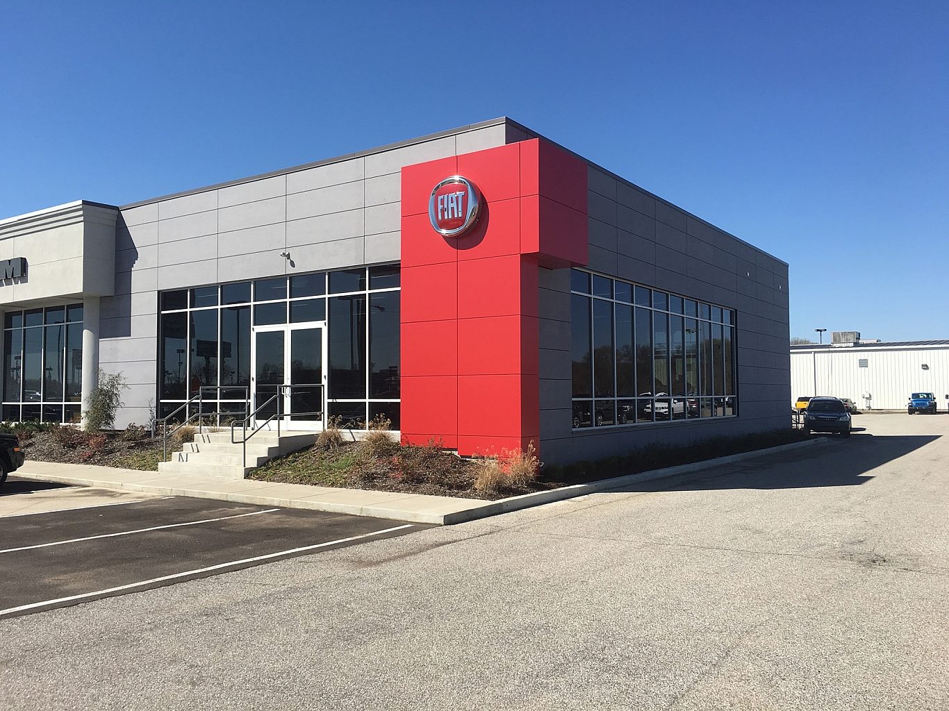 A Fiat car dealership with a red accent wall next to the main entrance.