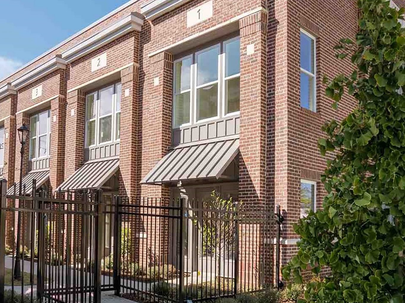 The exterior view of a two story apartment building with a metal fence around the outside