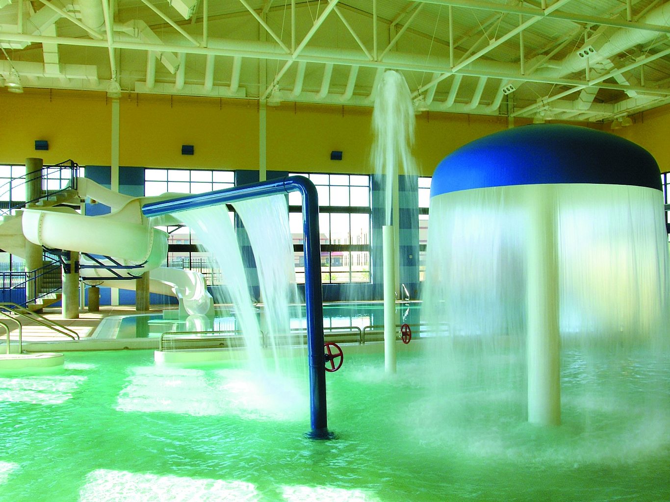 An indoor pool with a fountain and water slide for children