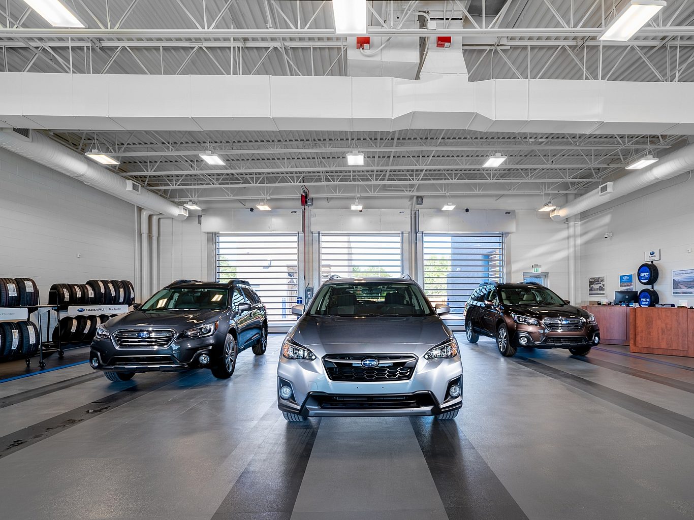 Subarus parked in the auto mechanic side of a car dealership.