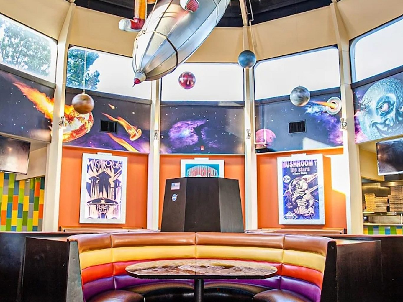 A restaurant booth with a space ship and planets hanging from the ceiling