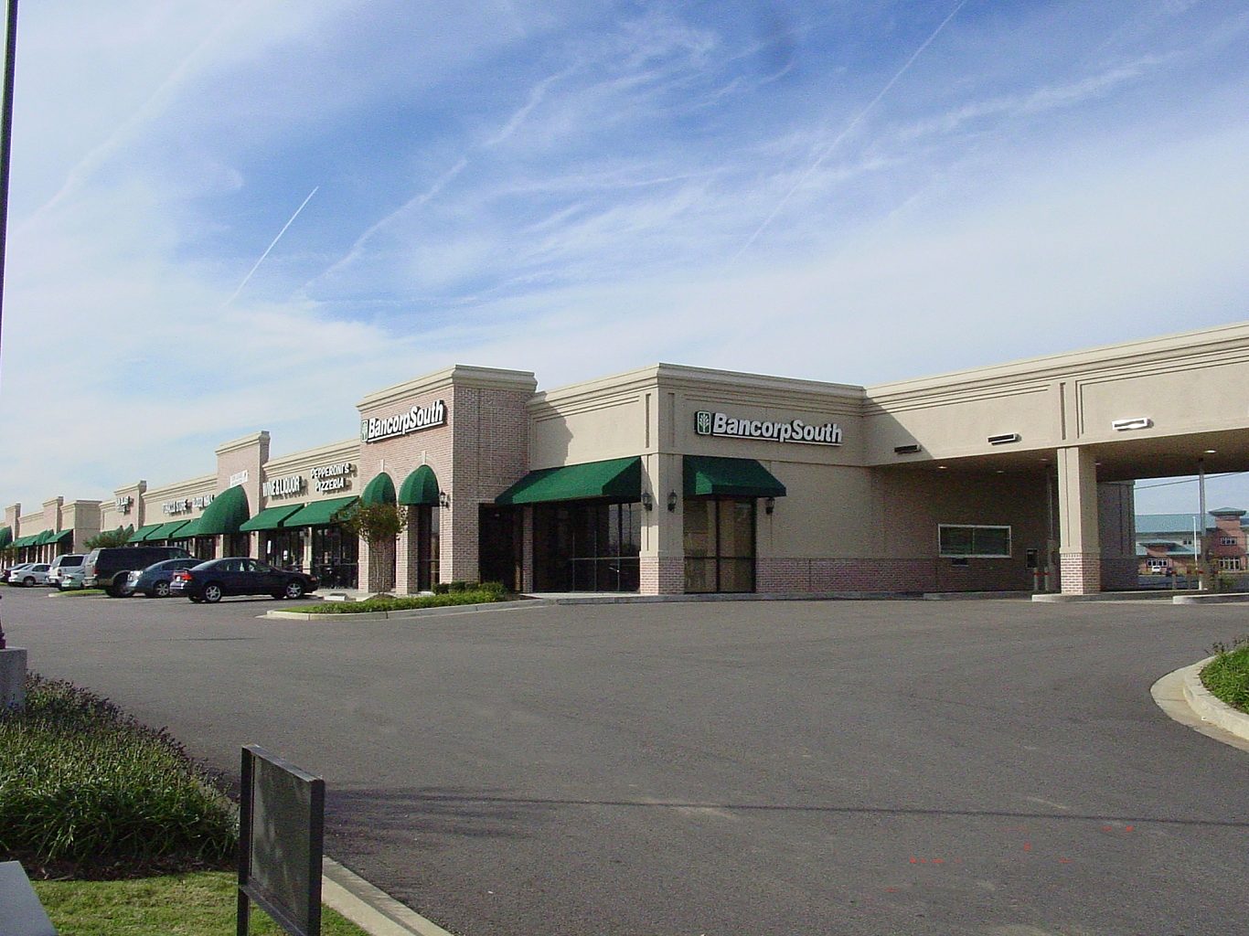 An outdoor shopping center with a drive through and green awnings
