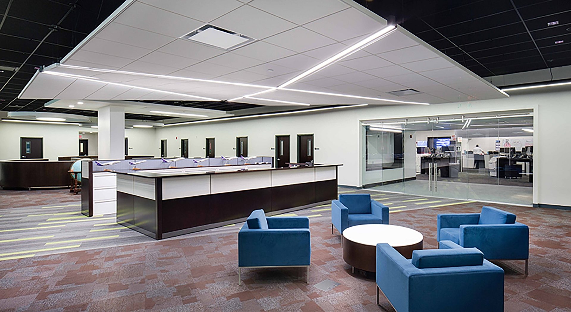 An office open space with a desk facing chairs and a table.