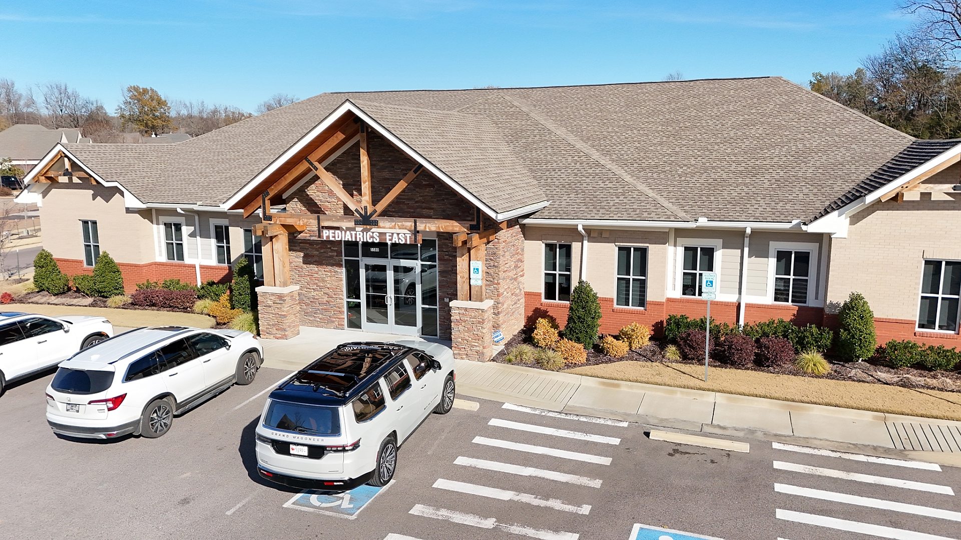 The exterior of a pediatrics clinic with three cars parked out front.