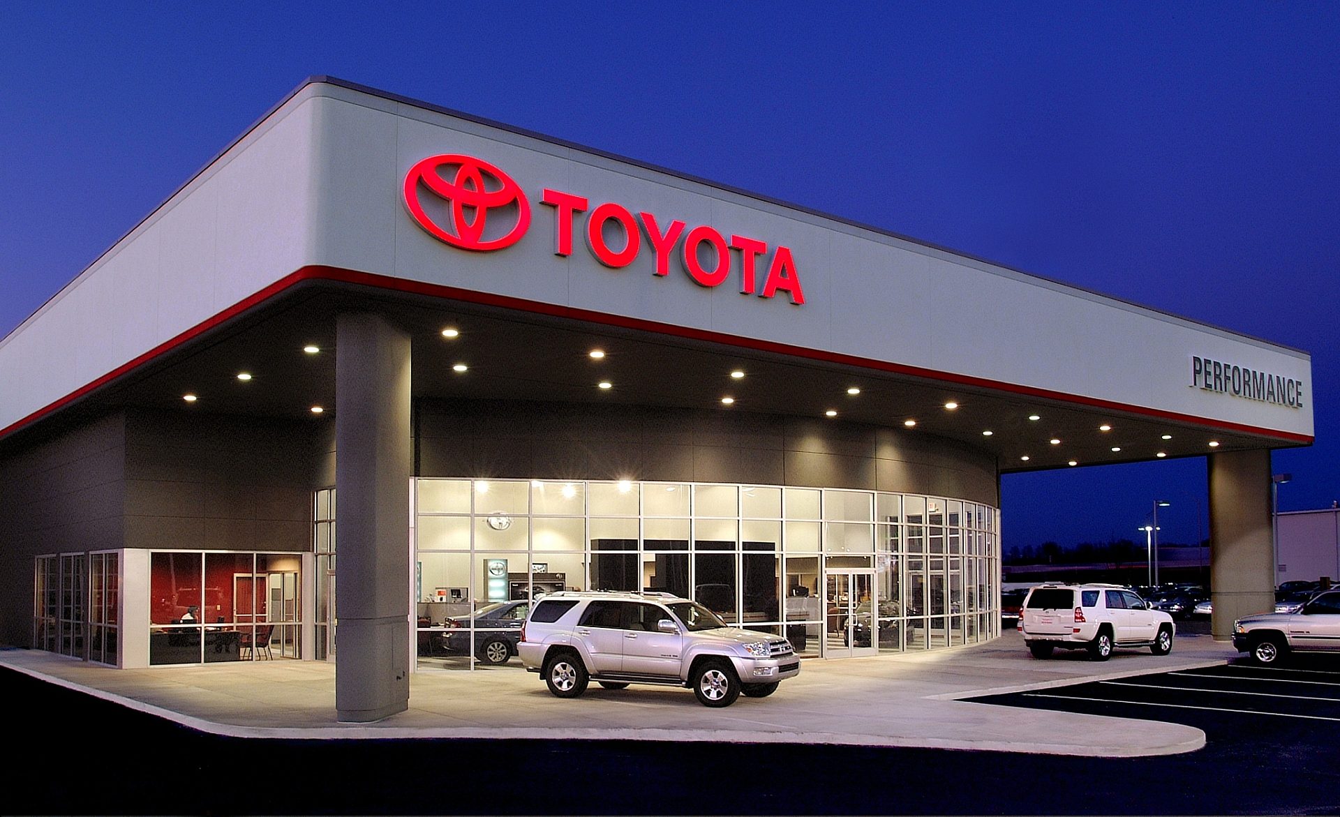 The exterior of a Toyota car dealership with a silver Toyota Forerunner parked out front