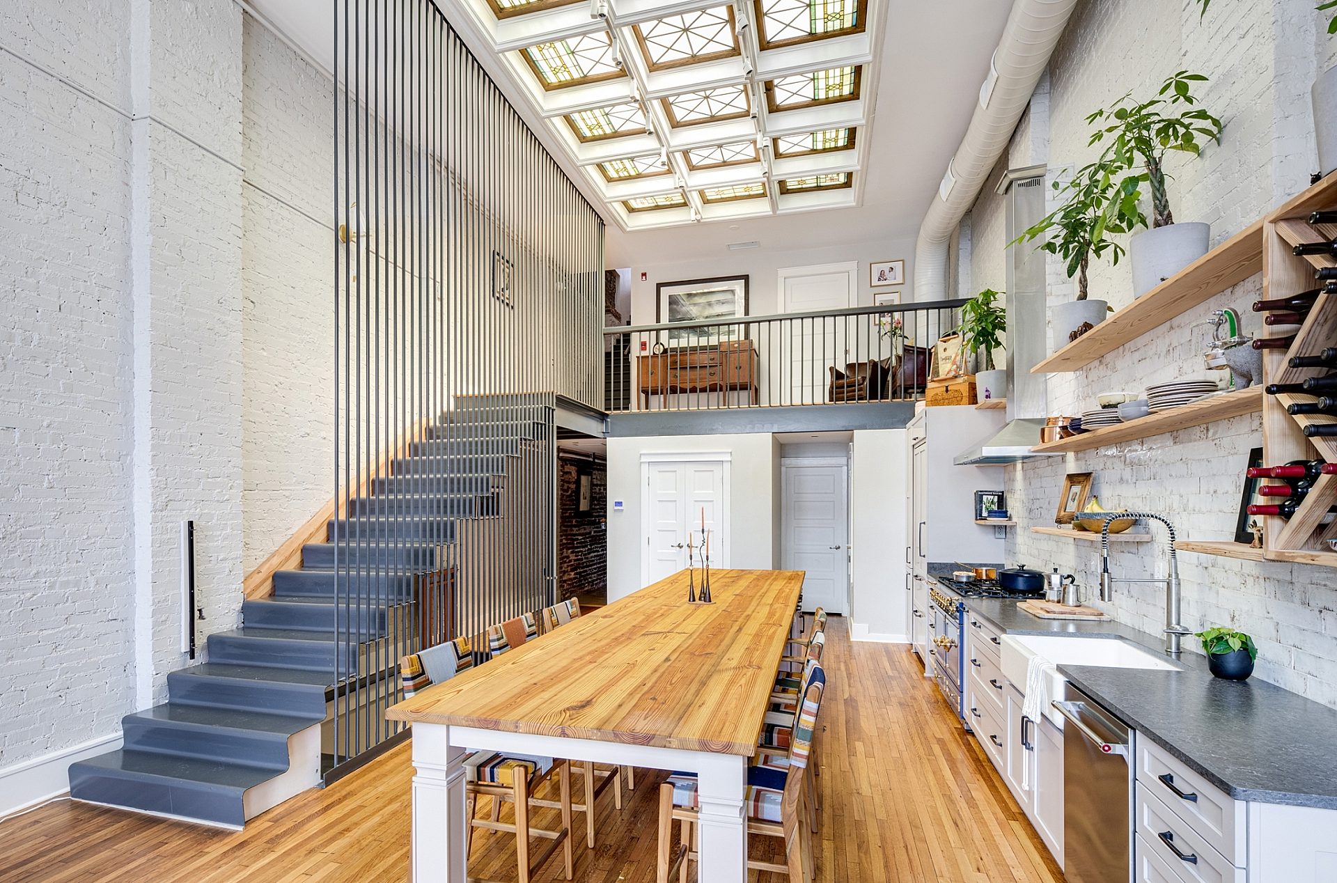 Open, modern kitchen with a dining room table in the center and stairs leading to the second level