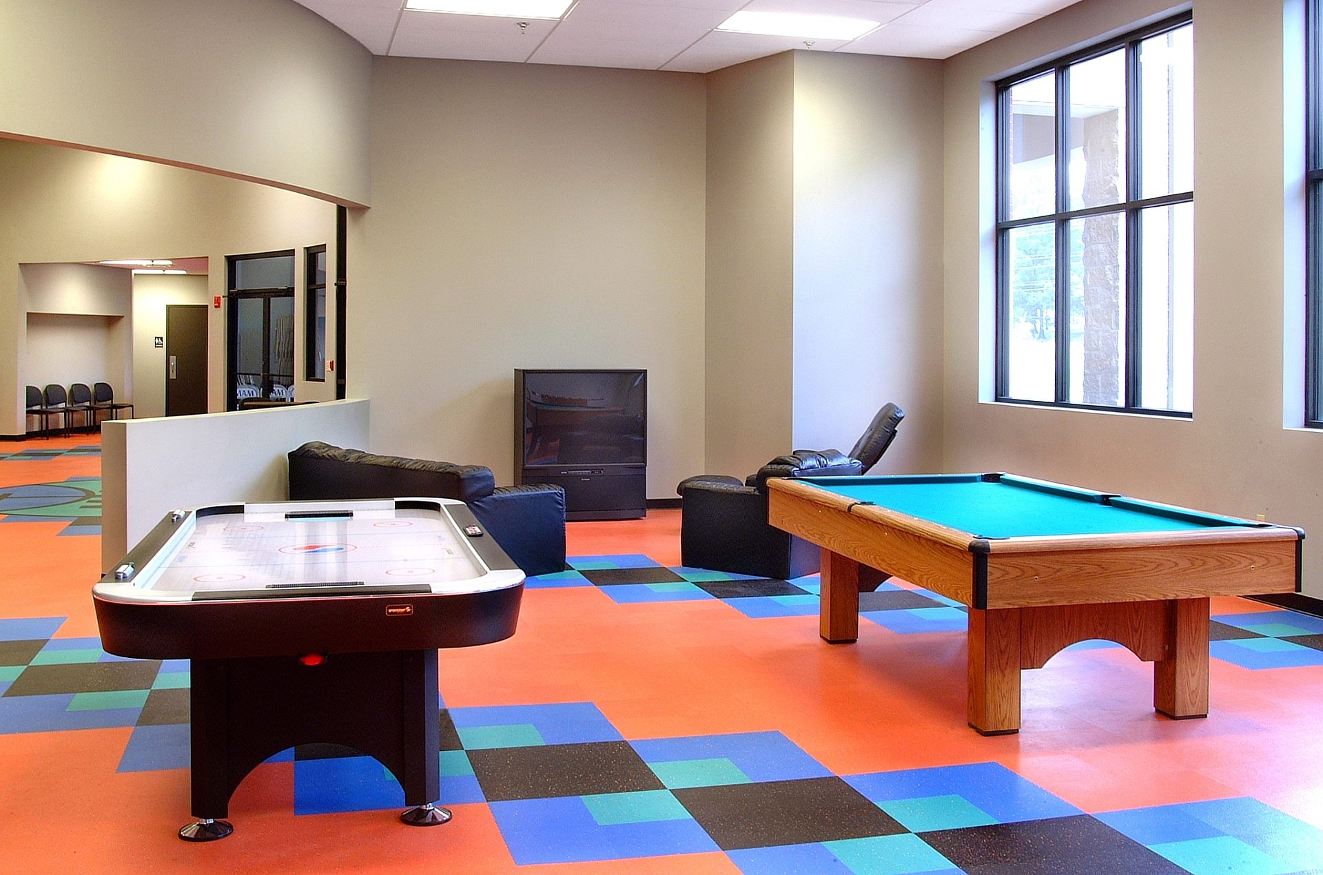 A pool table and an air hockey table in the lounge area of an athletic center.