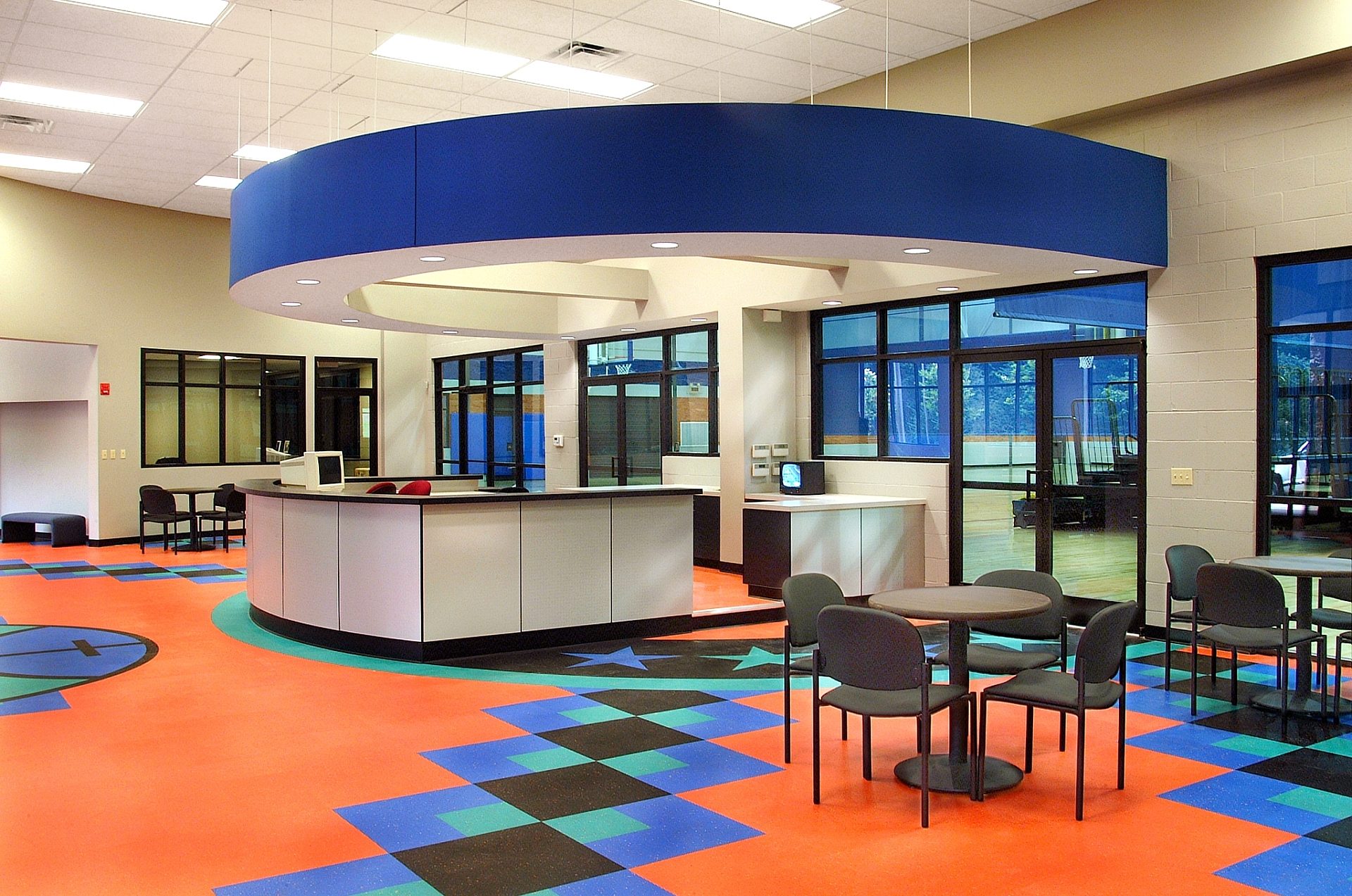 A lounge area with several tables and chairs in an athletic center.