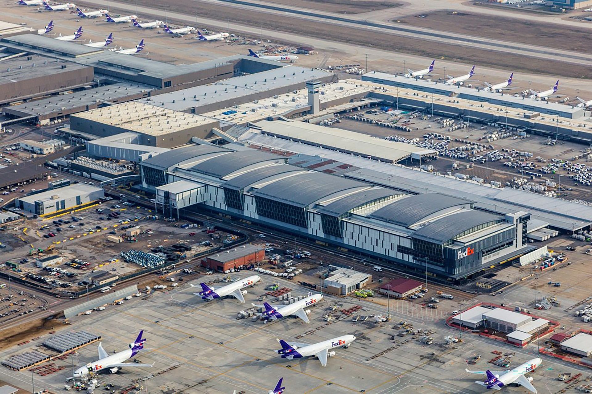 An aerial view of Fedex's sorting facility with several planes parked outside of it.