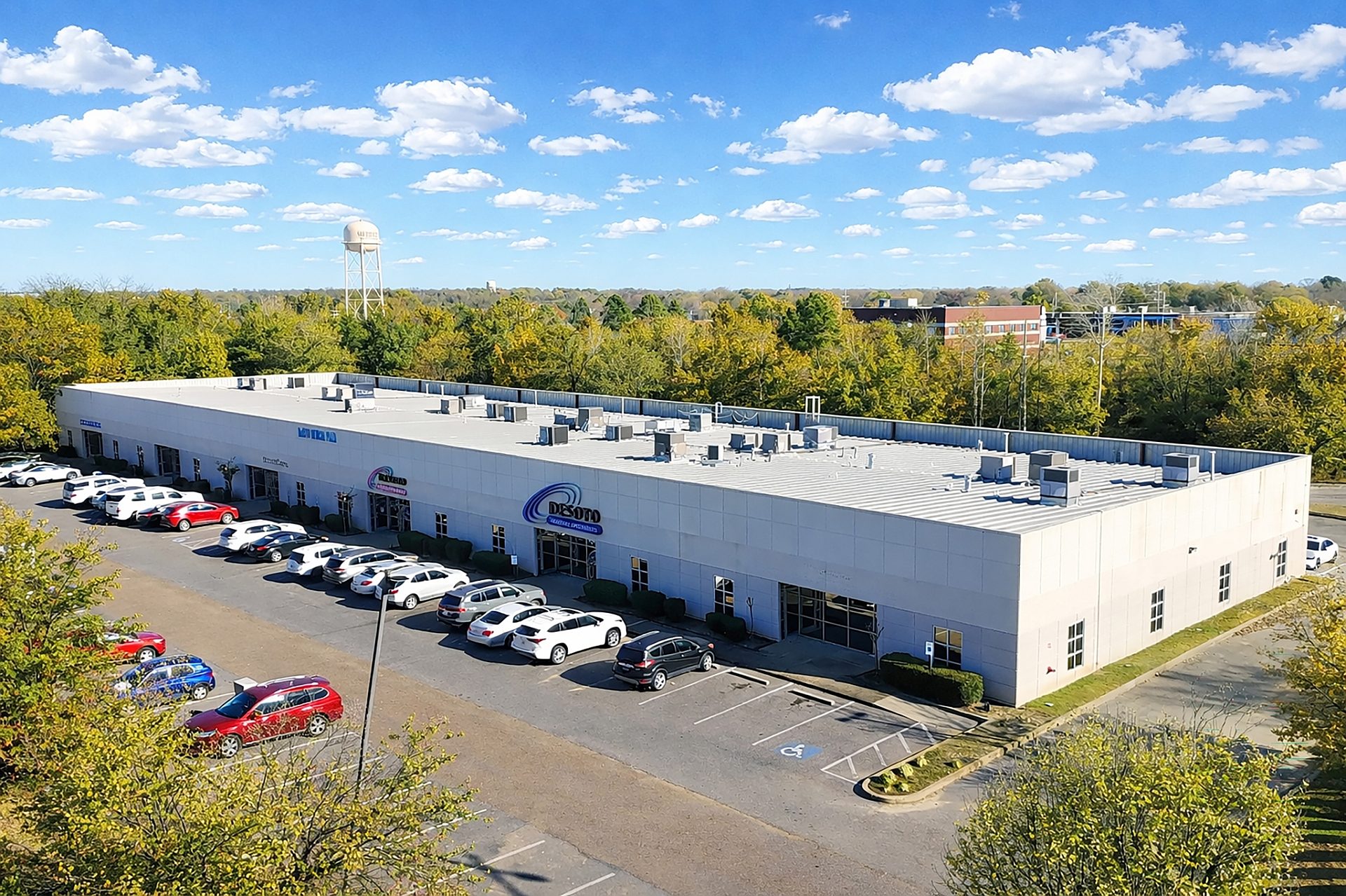 Aerial view of office buildings surrounded by trees with a water tower in the distance