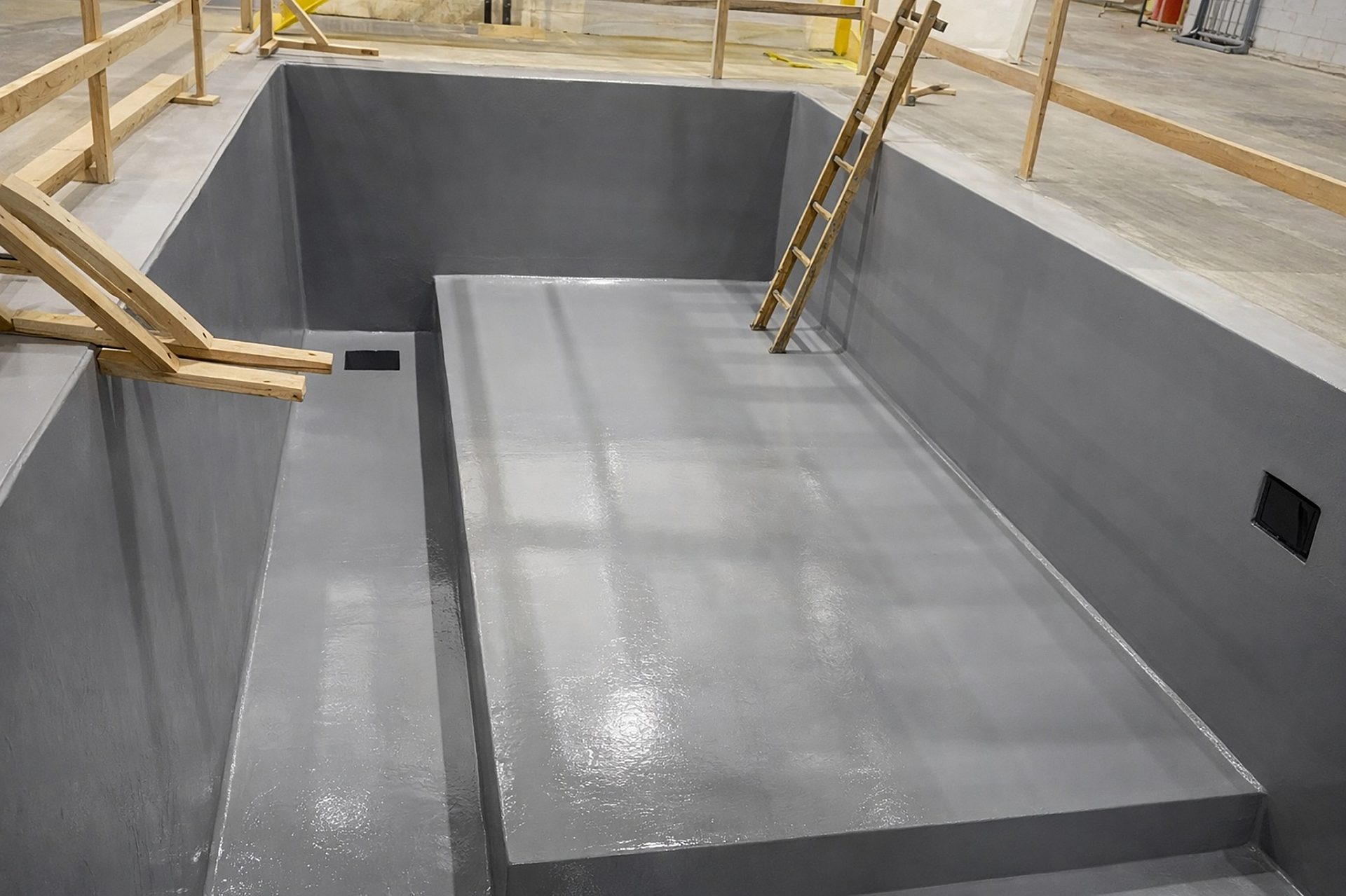 A cut-out pit in a construction zone with a ladder leading into it.