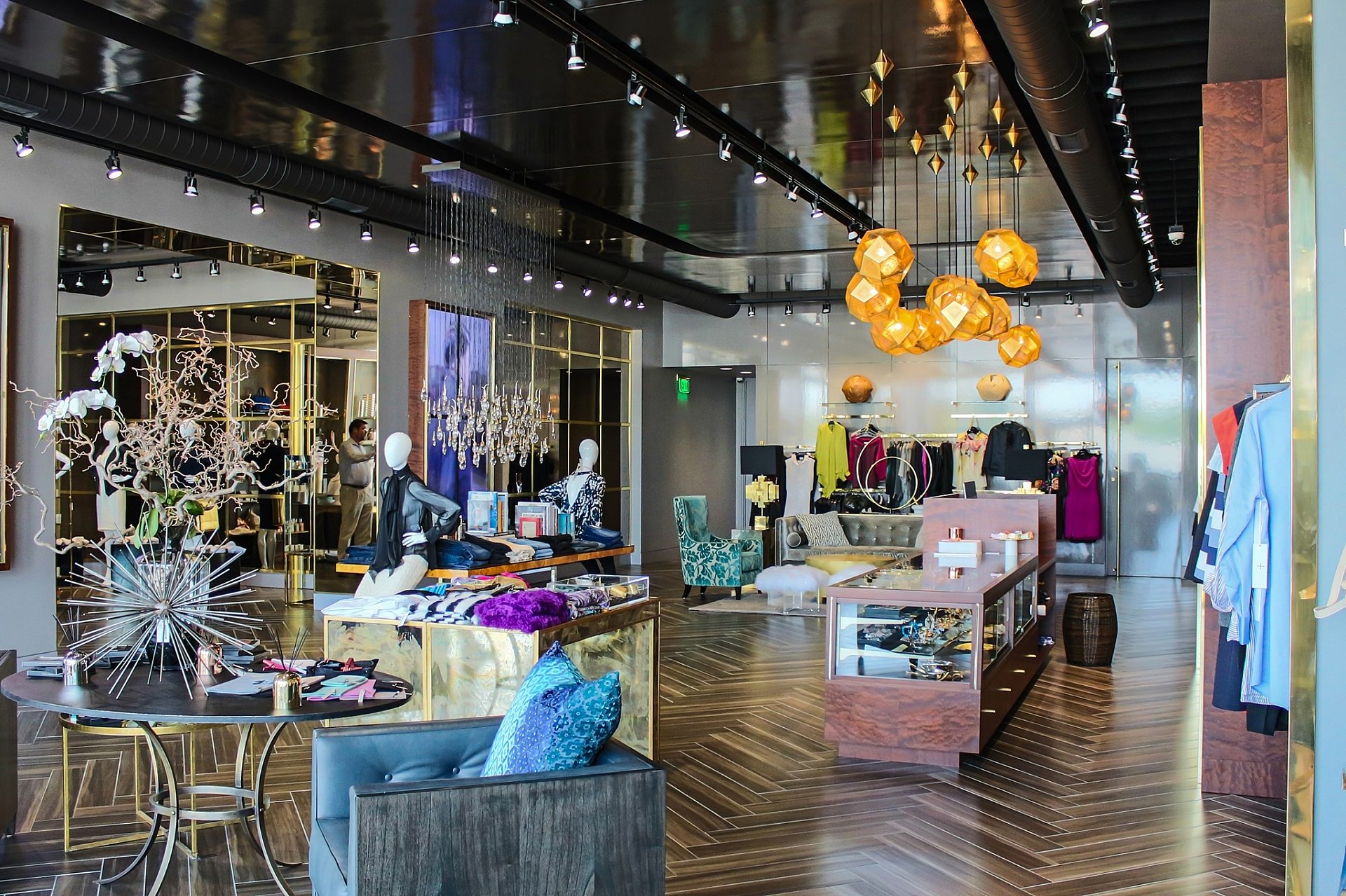 The interior of a clothing store, with a chair and table at the front and a display case on the right side.
