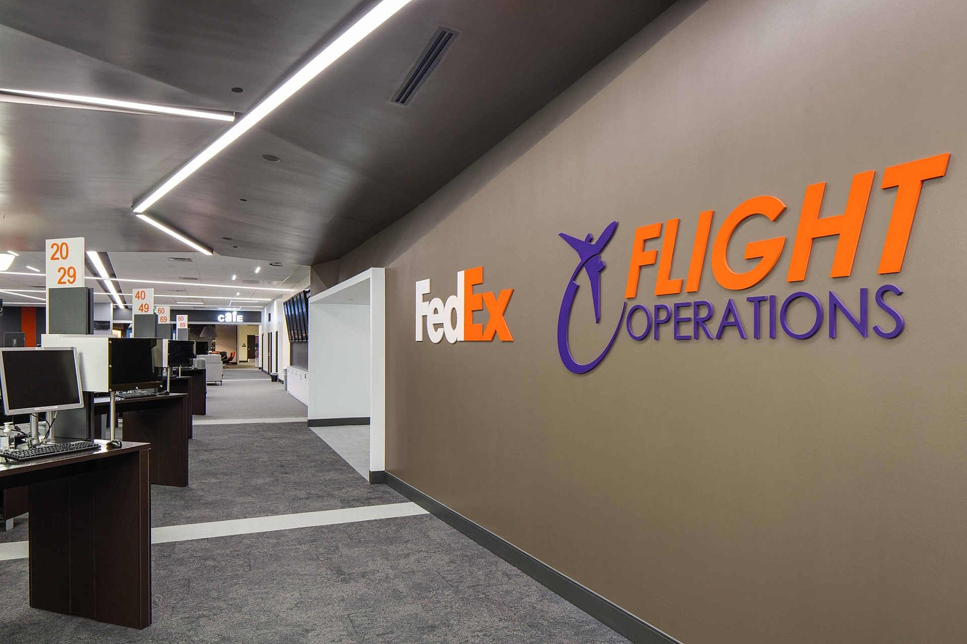 A hallway in a FedEx office building with desks with computers on them lining the left side.