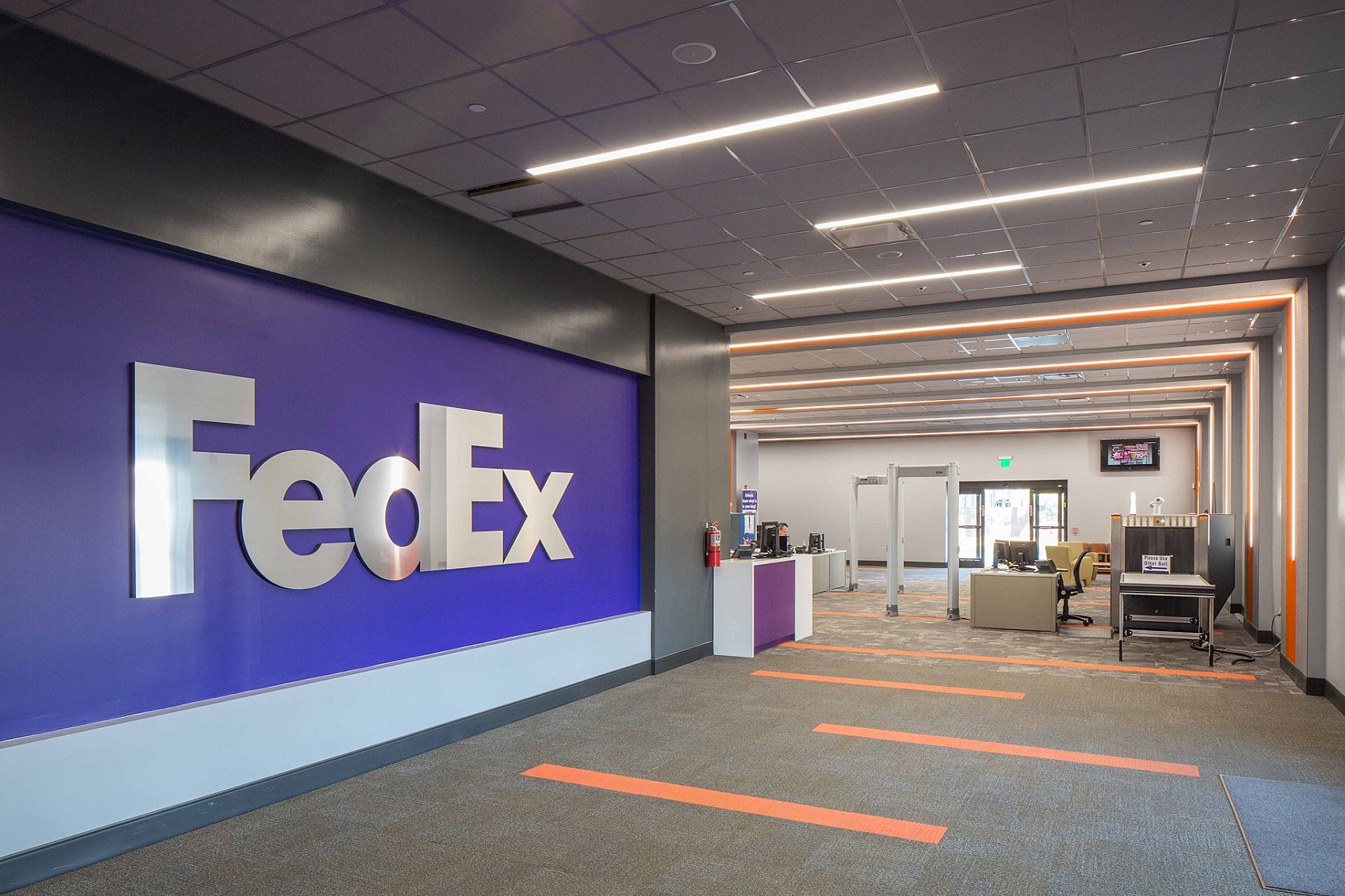 The entrance to a FedEx office space. FedEx is written on one wall, and a security entrance is seen on the right.