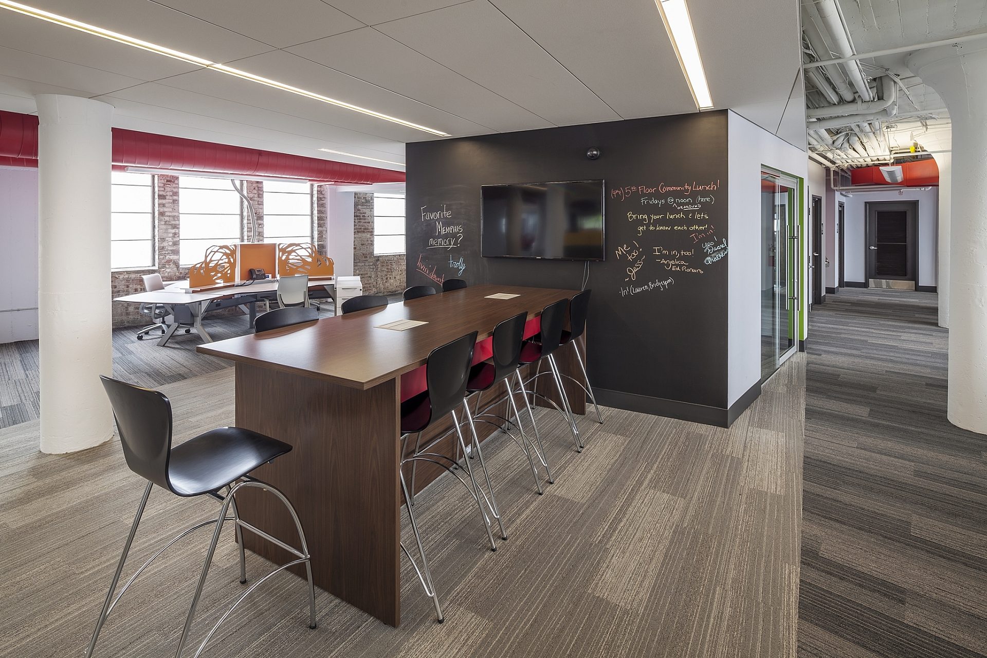 A common space in an office with an island and bar stools around it.
