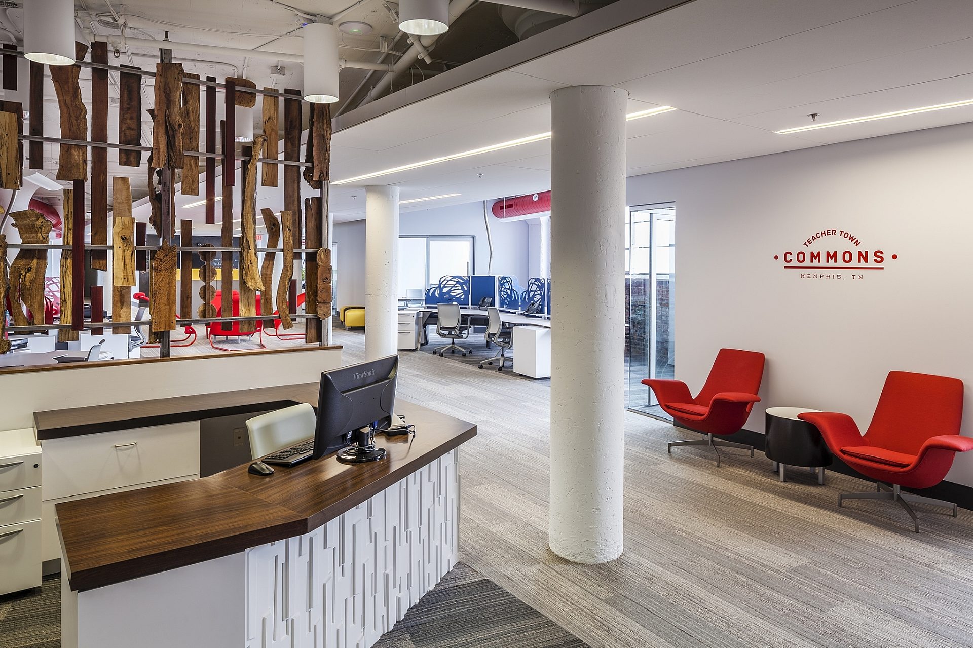 The entrance to an office space with red furniture and a logo featured on the wall