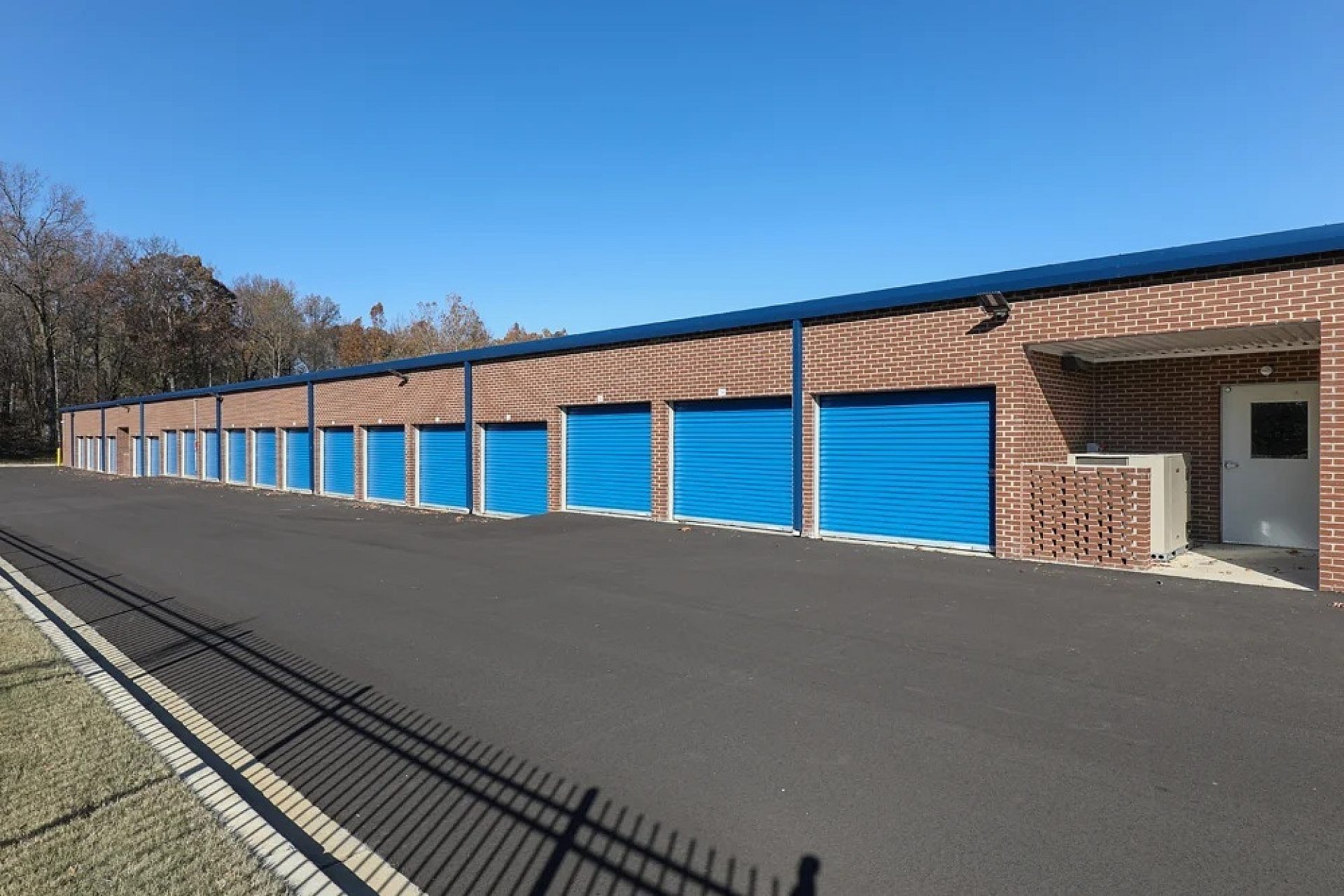 The exterior of a storage facility with blue garage-style doors on a brick building.