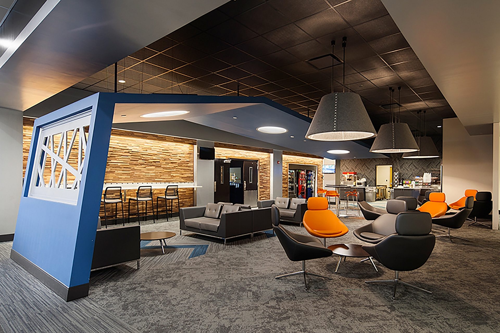 A modern lounge area in an office with several chairs, tables and couches.