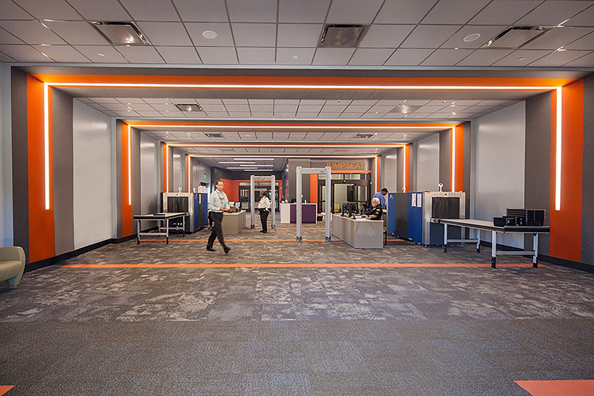 An open office space with a few desks lining the walls and people walking throughout.