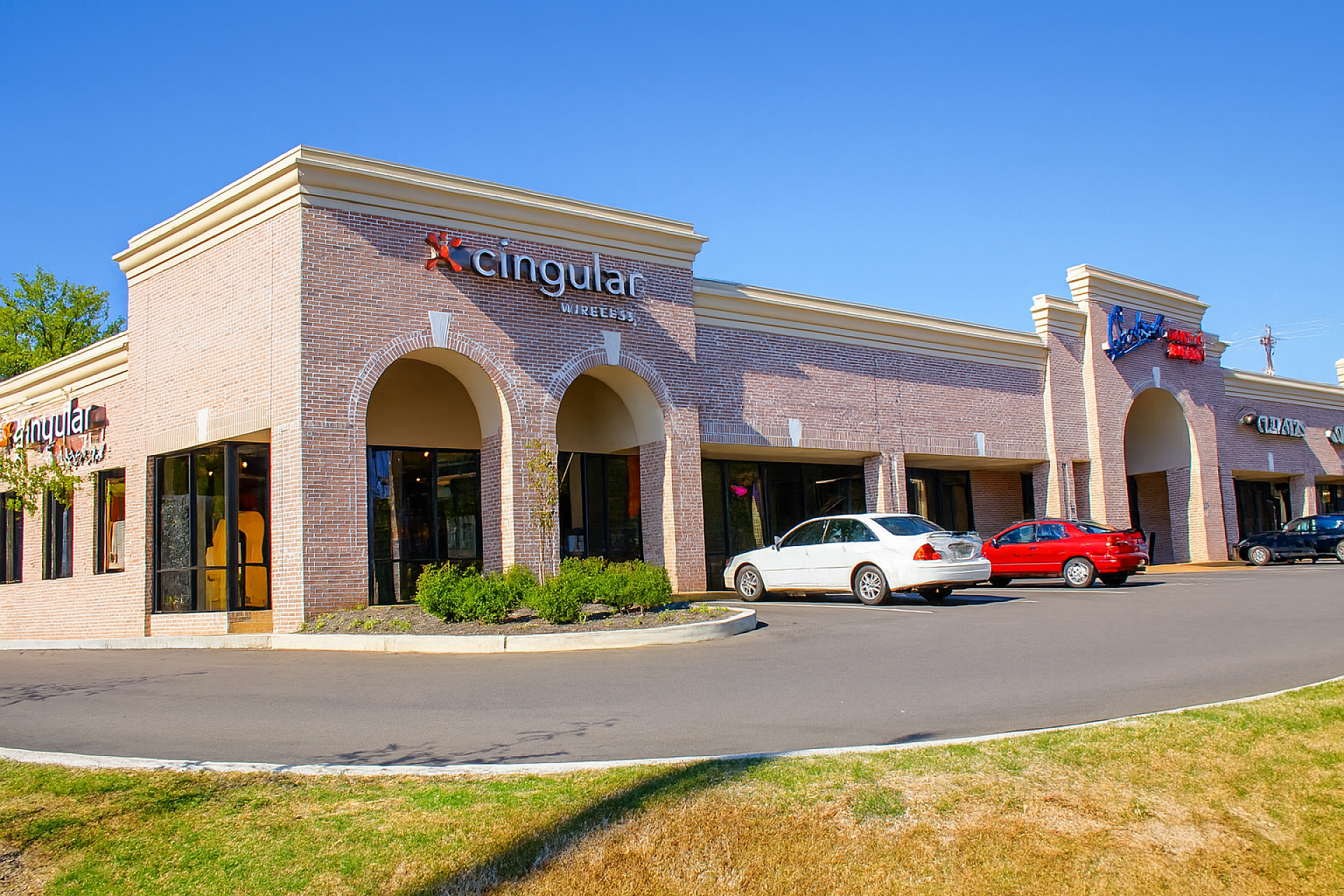 The exterior of a shopping center with two cars in the parking lot