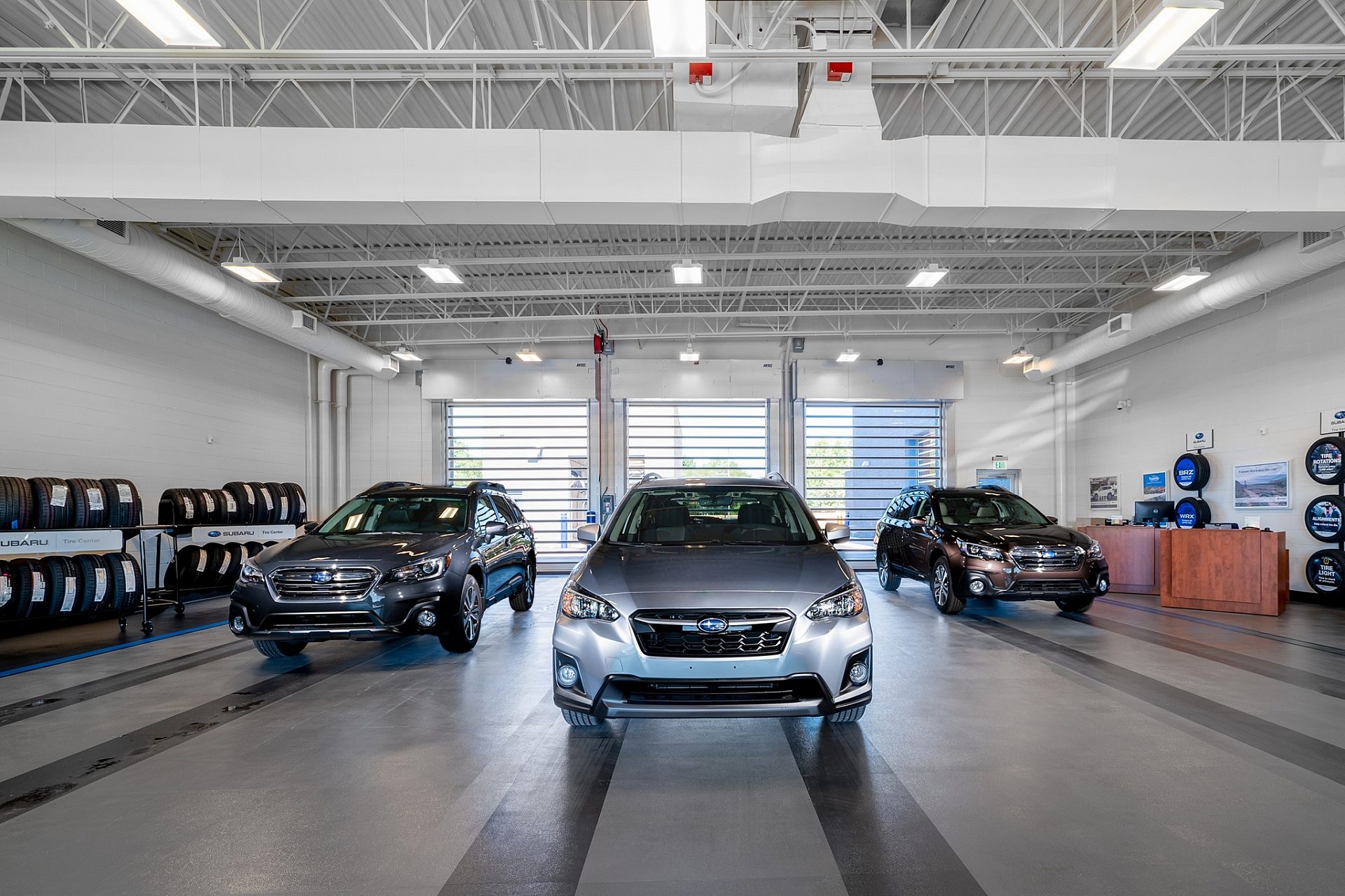Subarus parked in the auto mechanic side of a car dealership.
