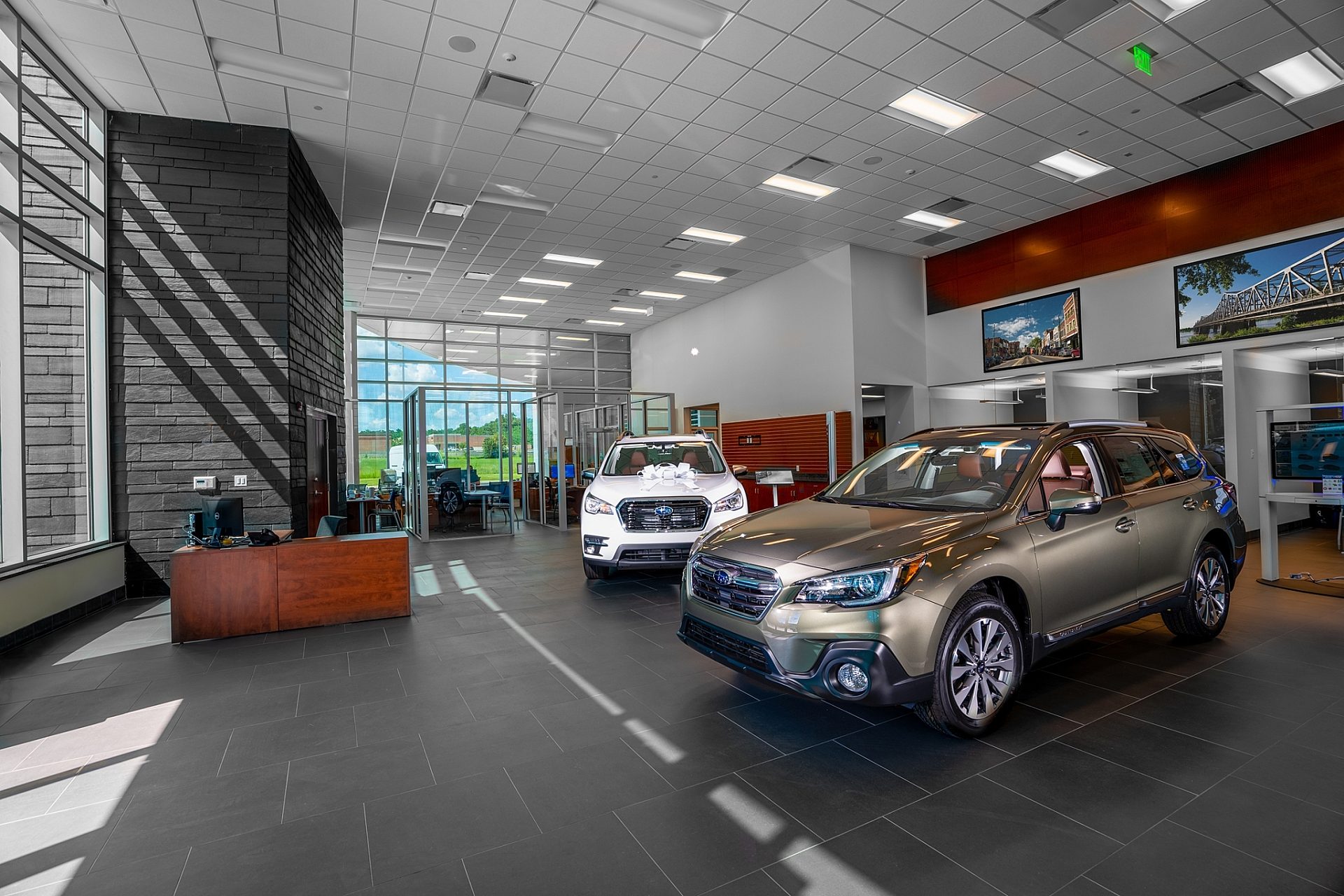 A car dealership lobby with two cars parked inside on display and a desk directly as you enter.