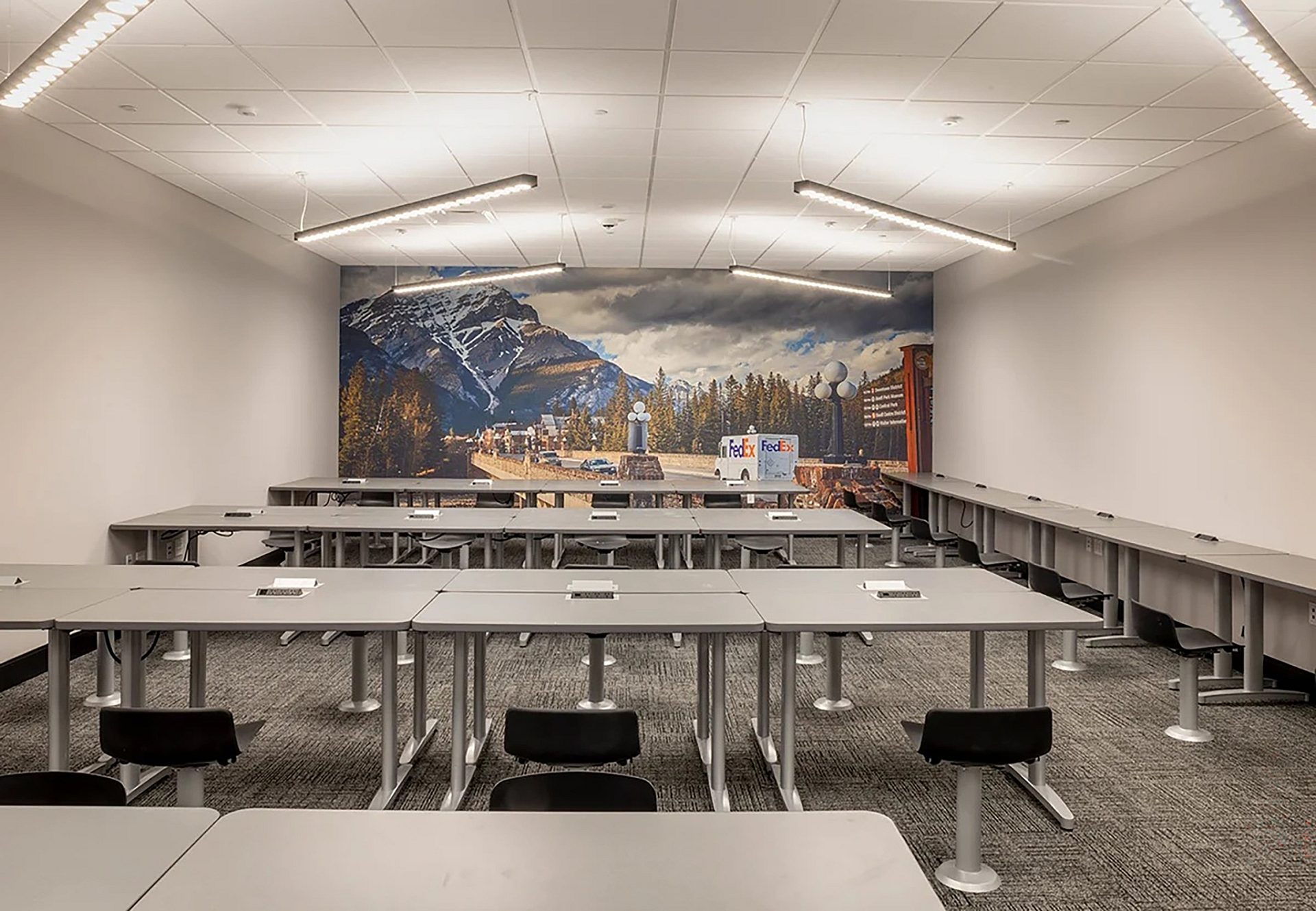 A room with several rows of gray desks. One row lines the wall.