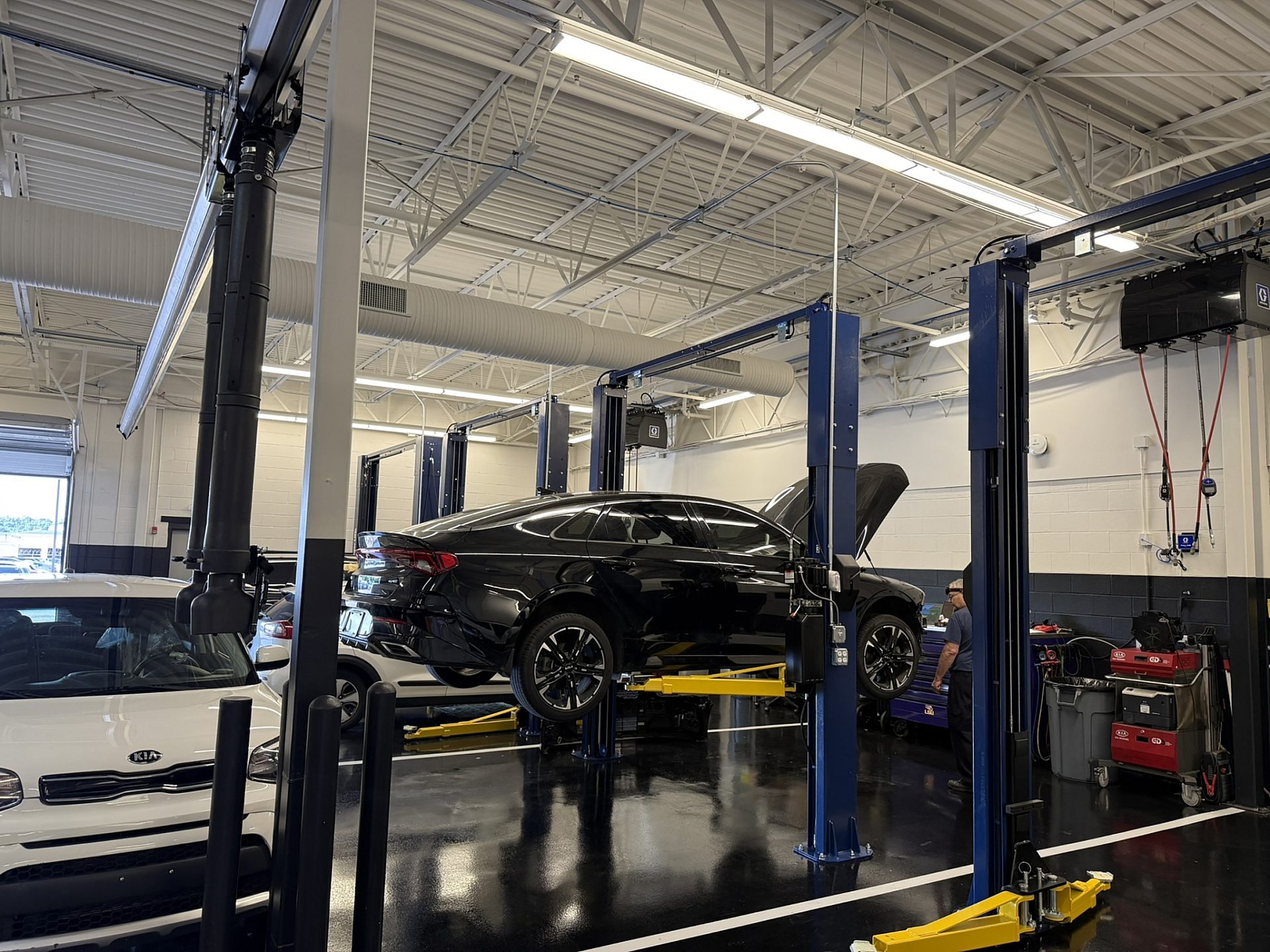 A black car in an auto mechanic shop with the hood popped open