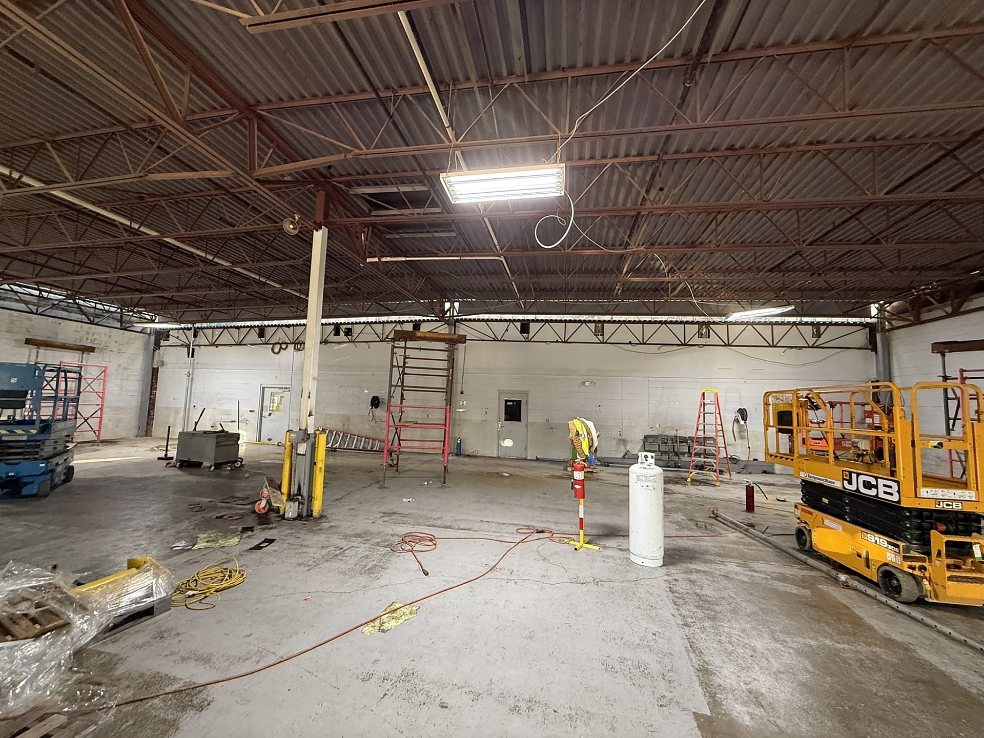 Interior construction zone with a concrete floor and walls and miscellaneous tools.