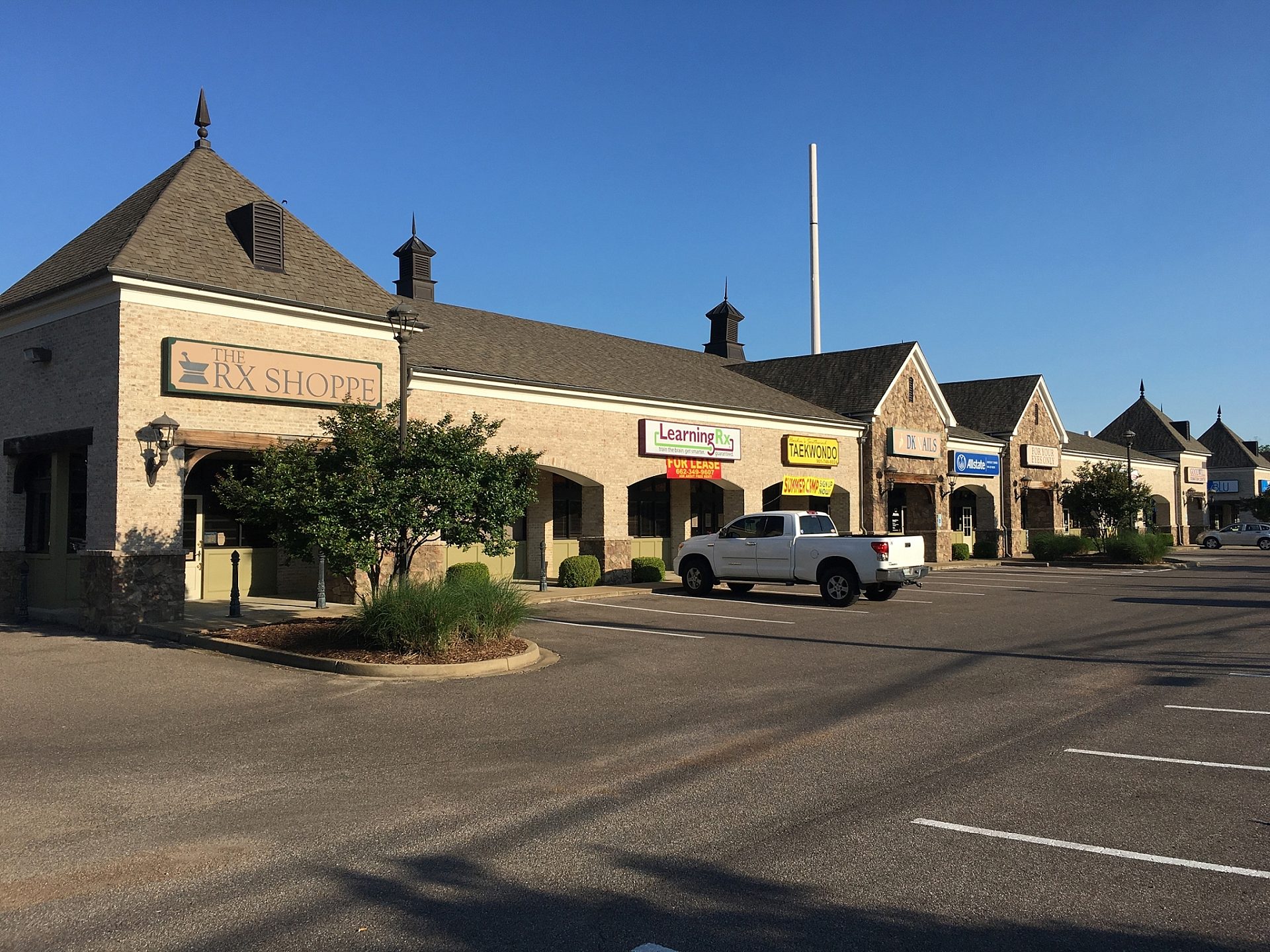 A retail shopping center with several tenants viewed from the parking lot.