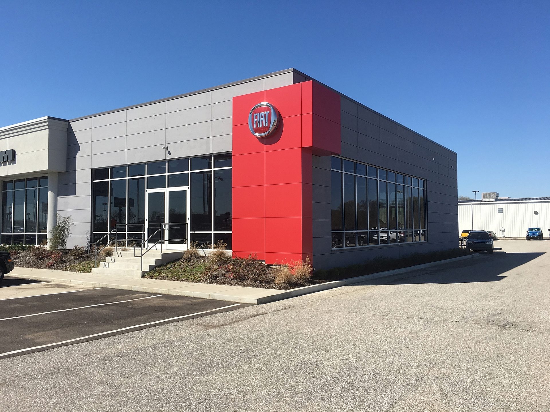 A Fiat car dealership with a red accent wall next to the main entrance.