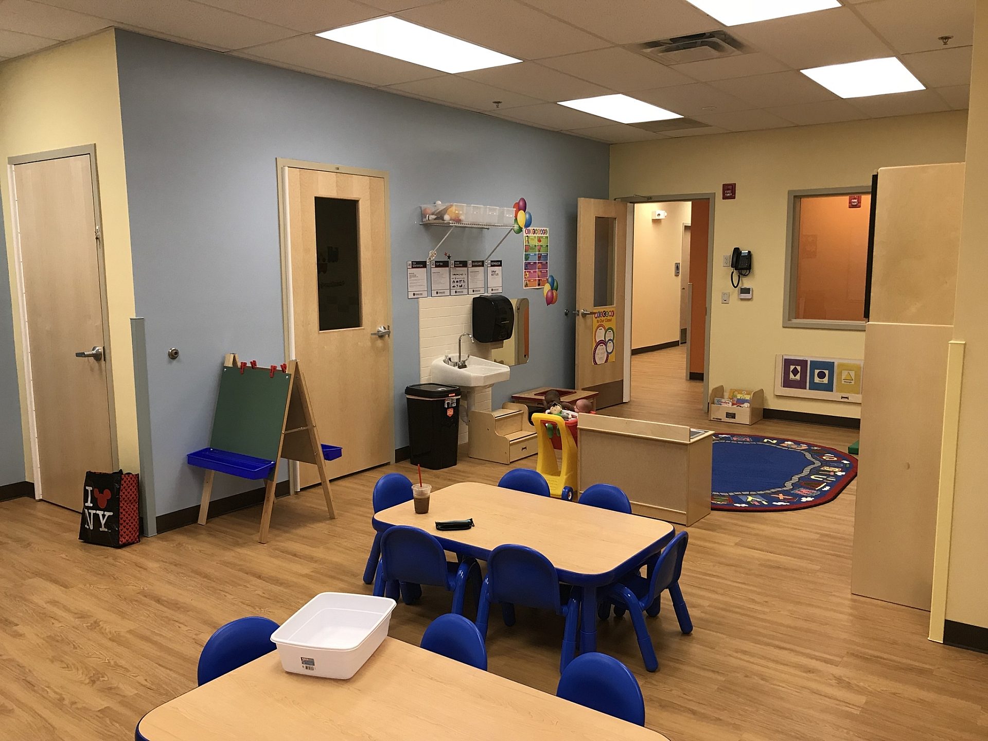 A classroom for elementary aged students with a play area at one end and desks in front of it.