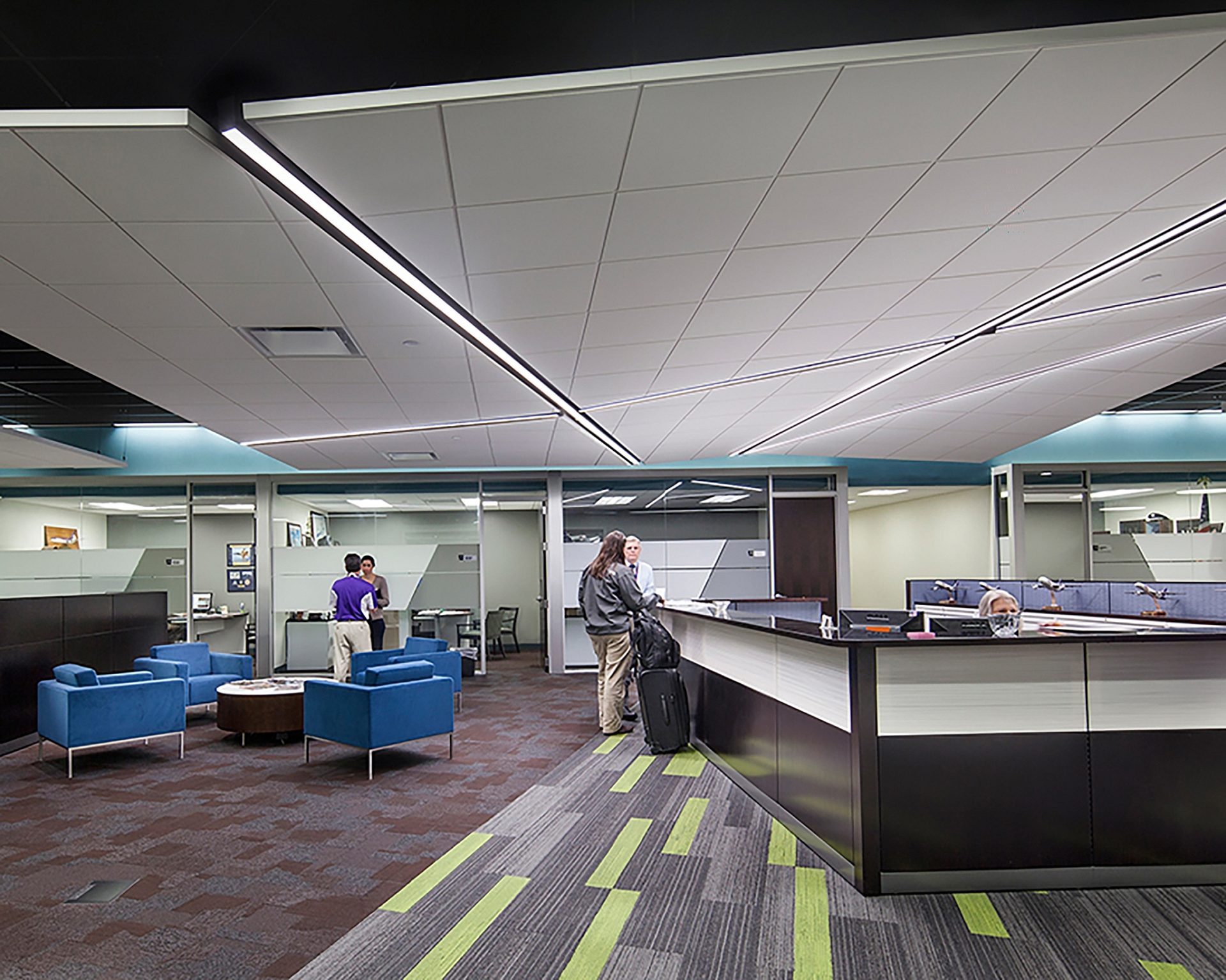 A desk faces the open area of an office with chairs and a table in front of it.