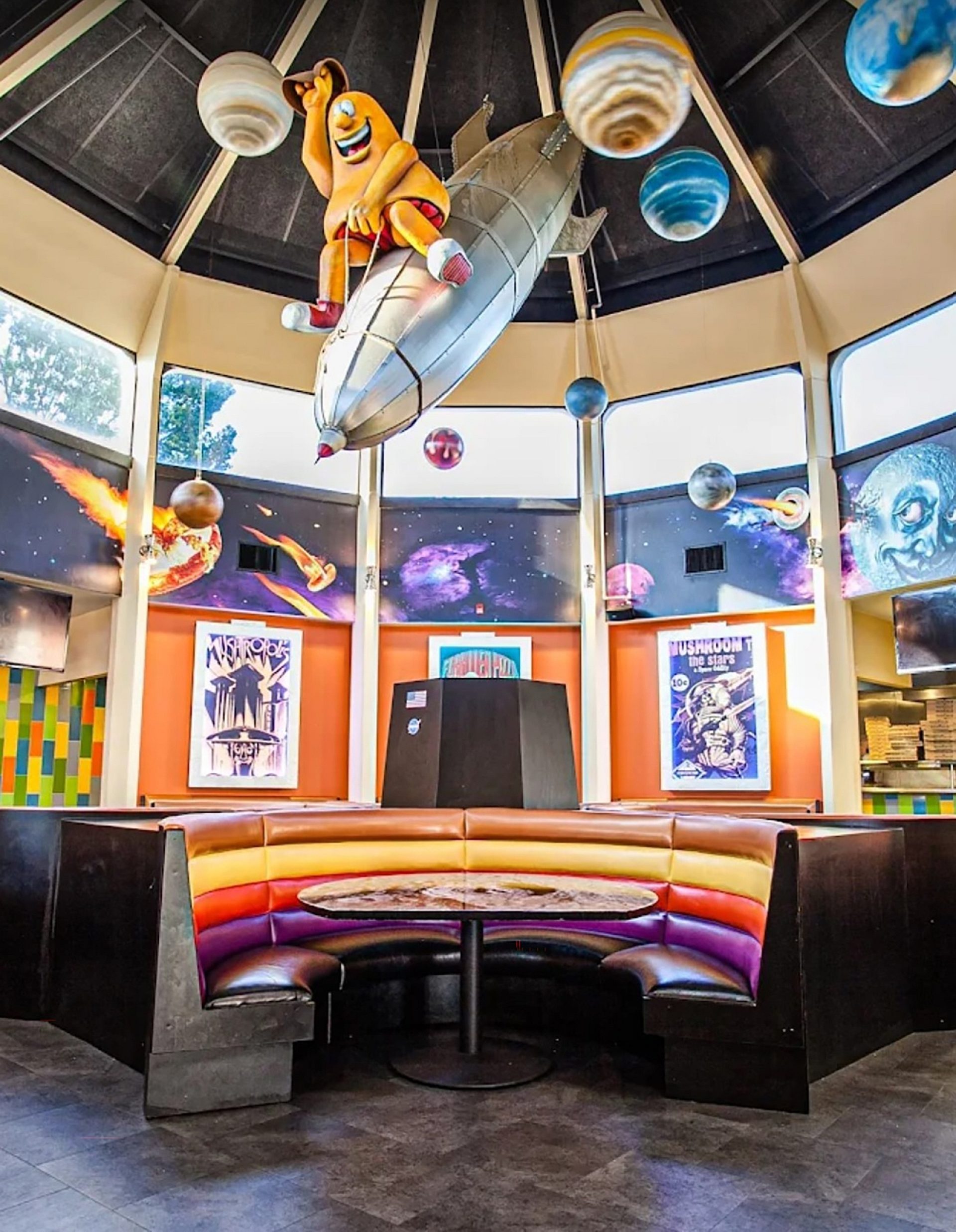 A restaurant booth with a space ship and planets hanging from the ceiling