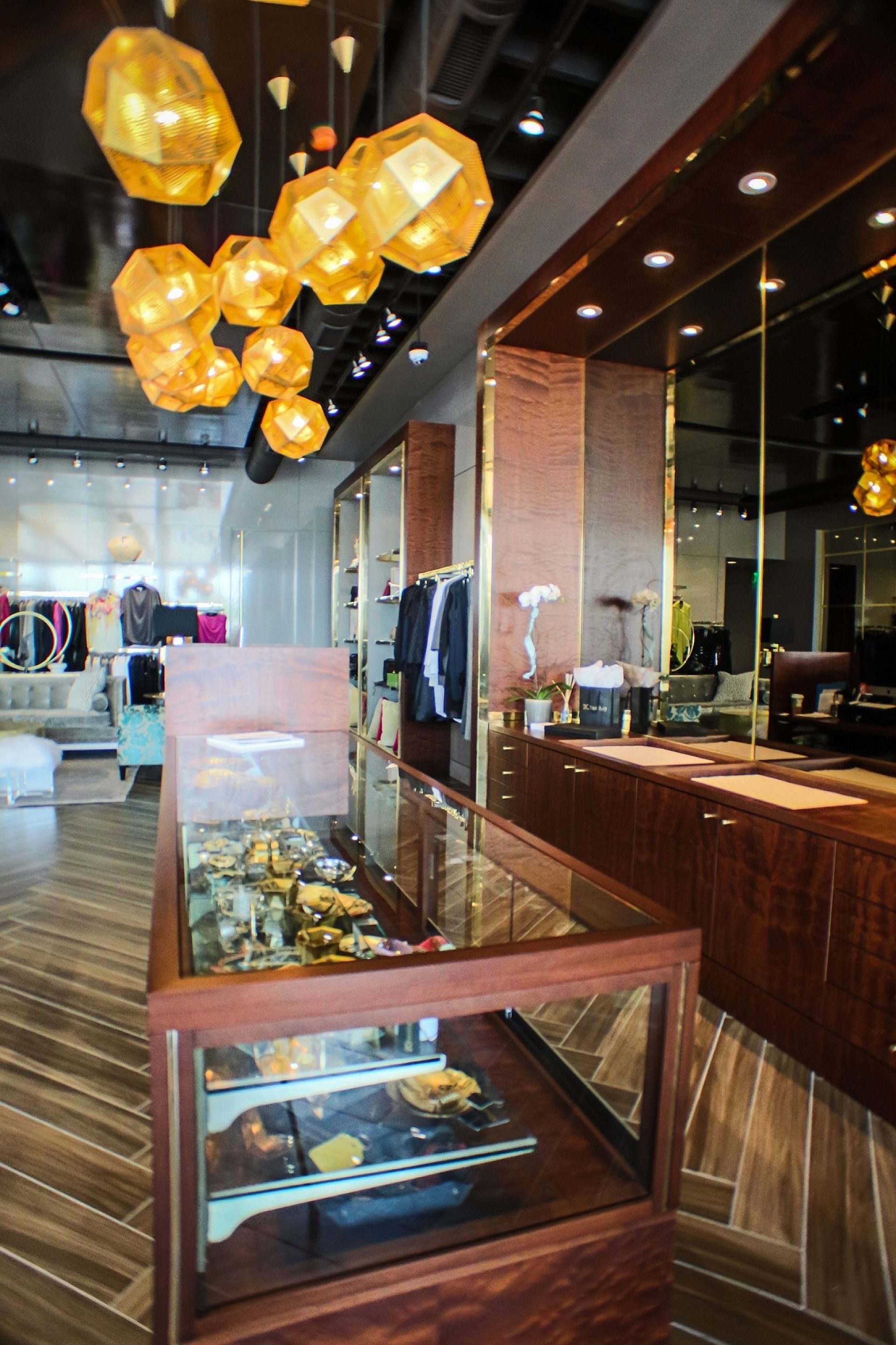 A display case in a clothing store with a hanging light fixture overhead and clothes hanging in the background