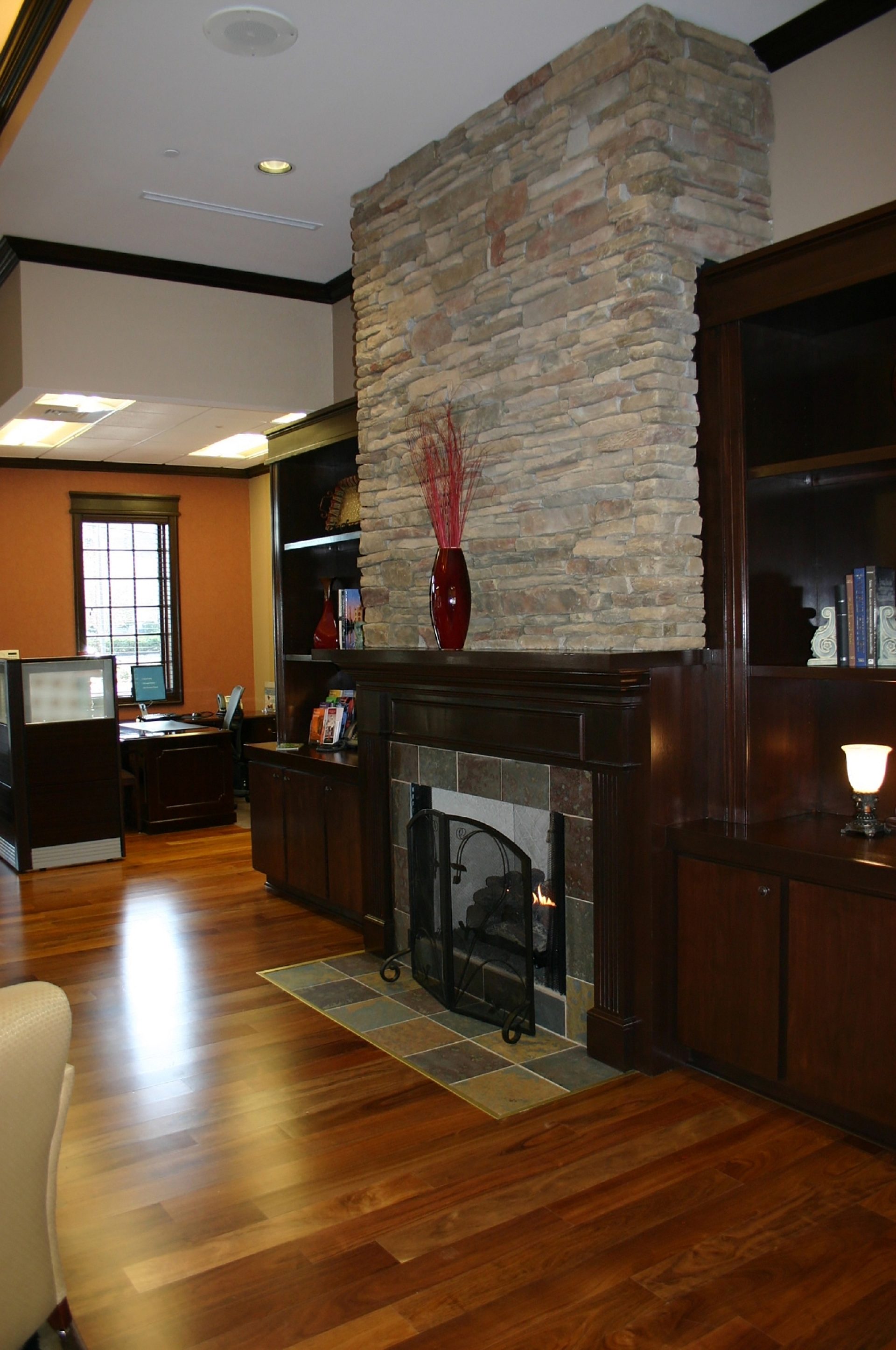 A fireplace in the open space of a bank with an office in the background.