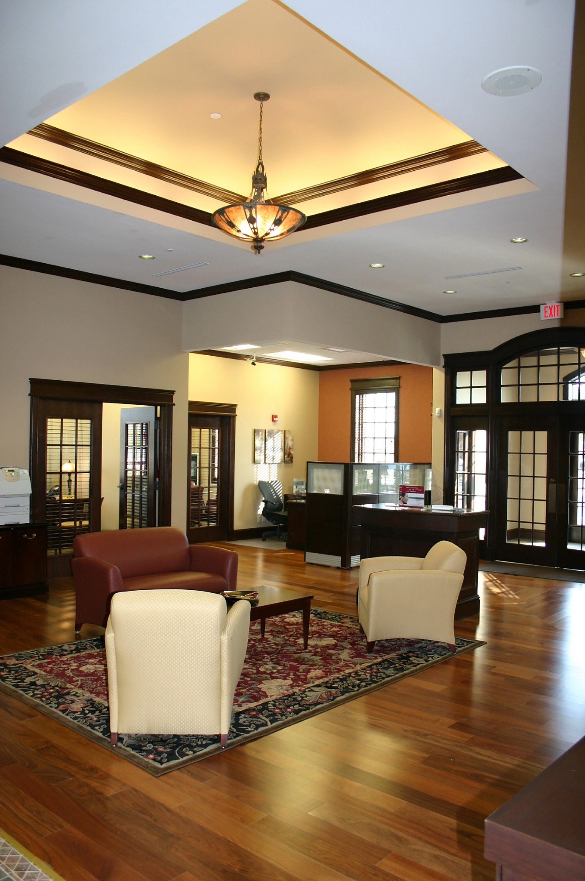 The interior waiting area of a bank with several seating options and a desk in the back corner.