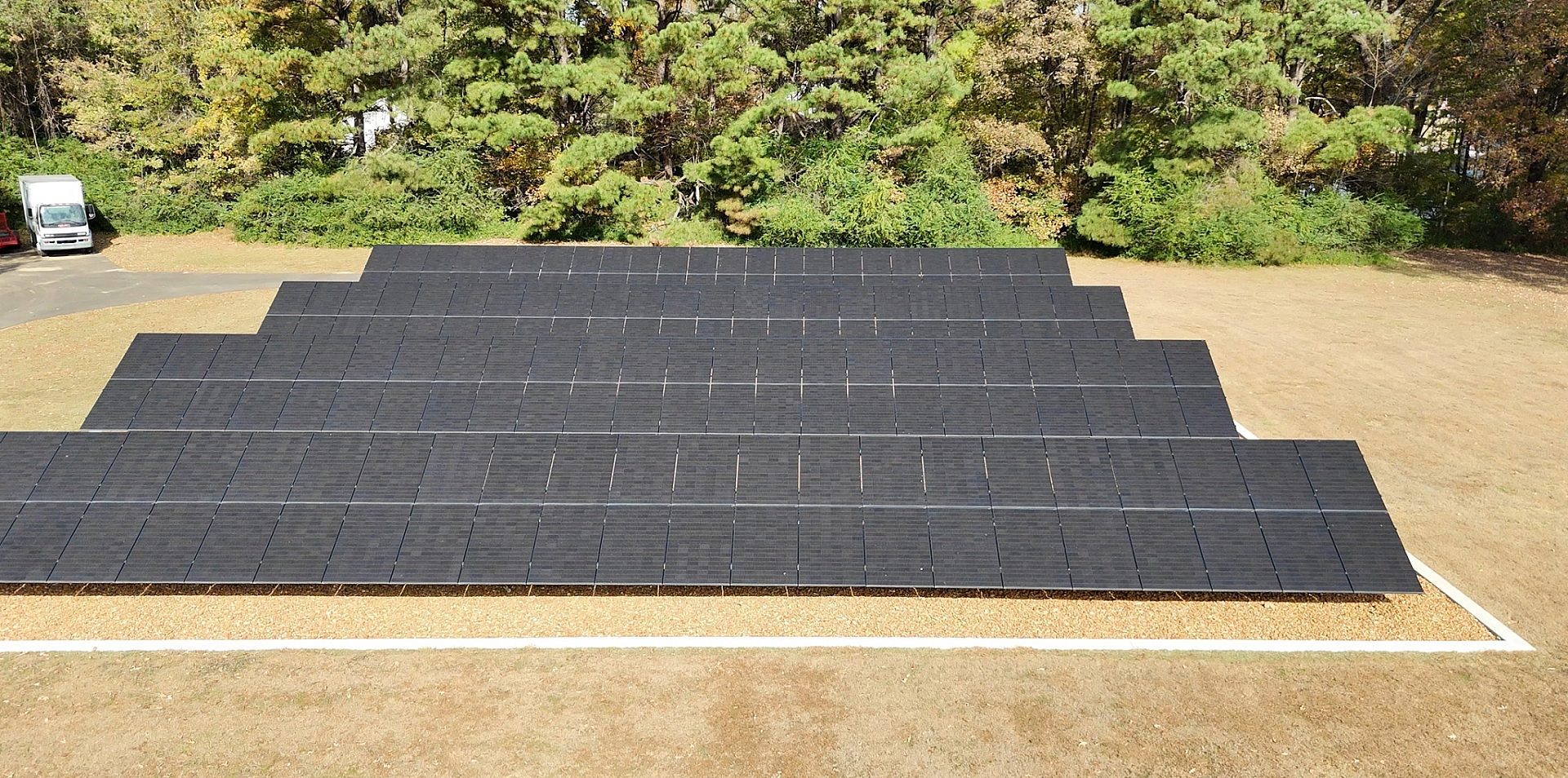 Front view of four rows of residential solar panels on a grass lawn