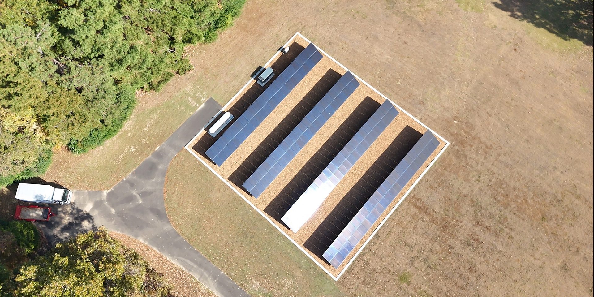 Aerial view of four rows of residential solar panels on a grass lawn