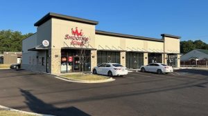 The exterior of a shopping center with a Smoothie King in the far left store.
