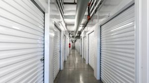 A hallway in a storage facility with white, metalic storage shed doors lining it.
