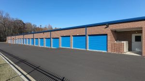 The exterior of a storage facility with blue garage-style doors on a brick building.