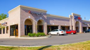 The exterior of a shopping center with two cars in the parking lot