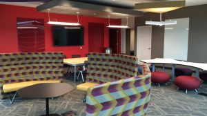 A corporate classroom with several seating options, including benches lining a wall and stools at a table.