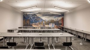 A room with several rows of gray desks. One row lines the wall.