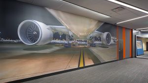A floor to ceiling visual of a plane on the wall of an office.