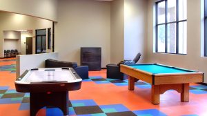 A pool table and an air hockey table in the lounge area of an athletic center.